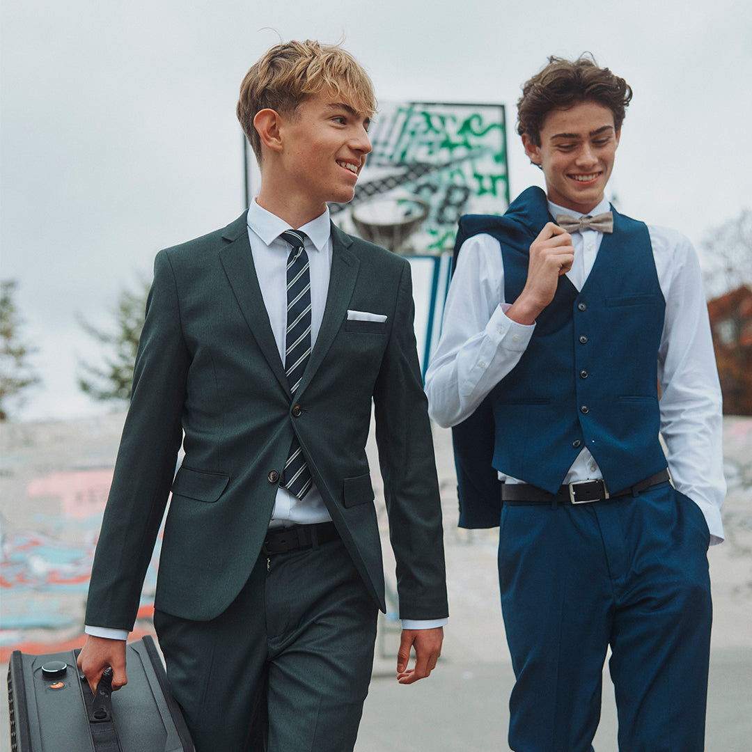 To konfirmander i habit med mappe og jakke over skulderen