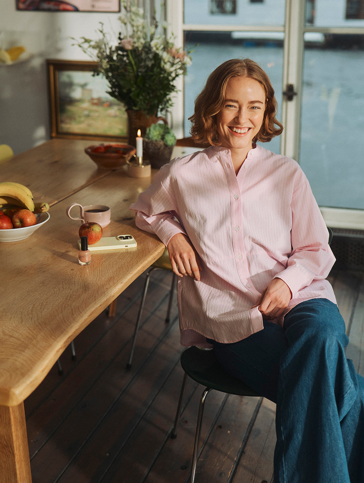 Kvinde iført lyserød løs skjorte og mærke jeans i en husbåd.