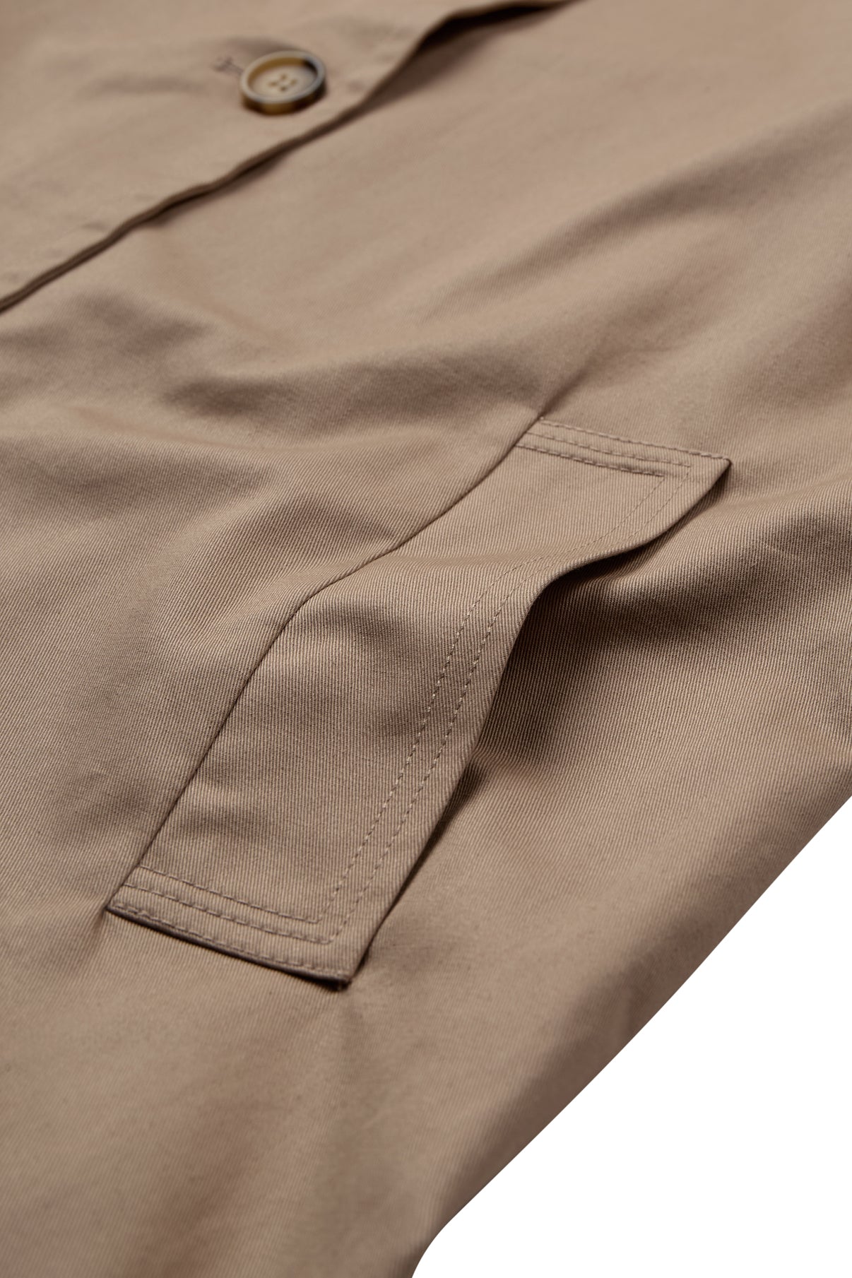 Beige trenchcoat med skrålomme og skjult knaplukning i blødt stof.