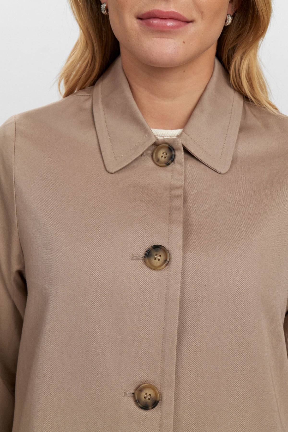 Beige trenchcoat med klassiske knapper og krave, glat stof og stilfuldt snit.