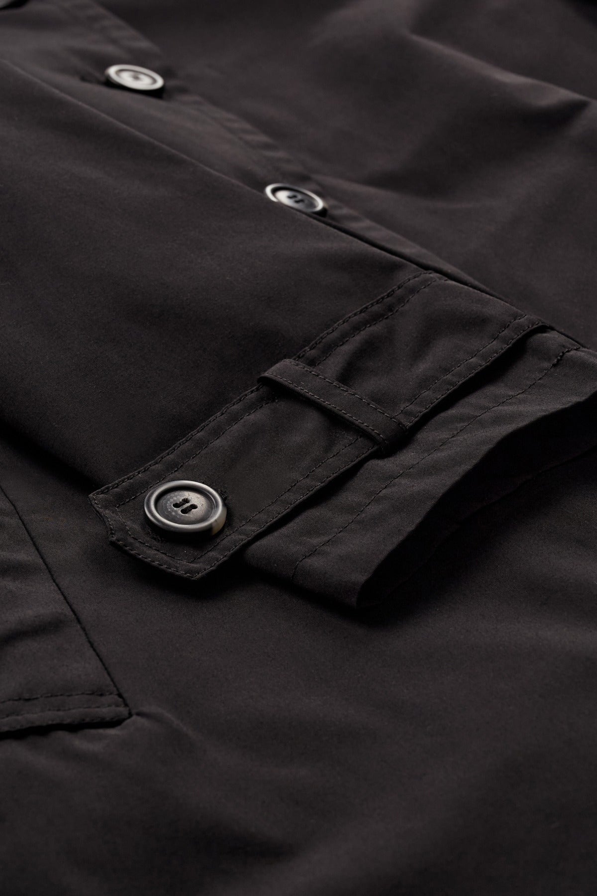 Oversize sort trenchcoat i kraftig stof med knapper og justerbar manchet.