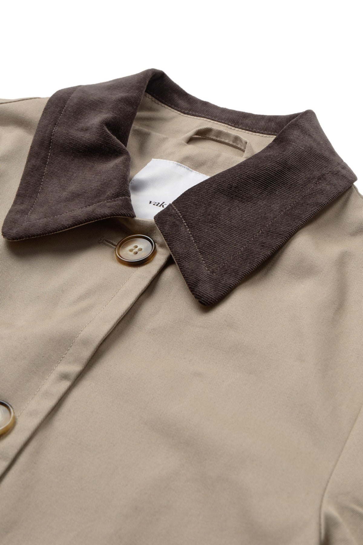 Beige kort jakke med mørk brun fløjlskrave og knapper foran.