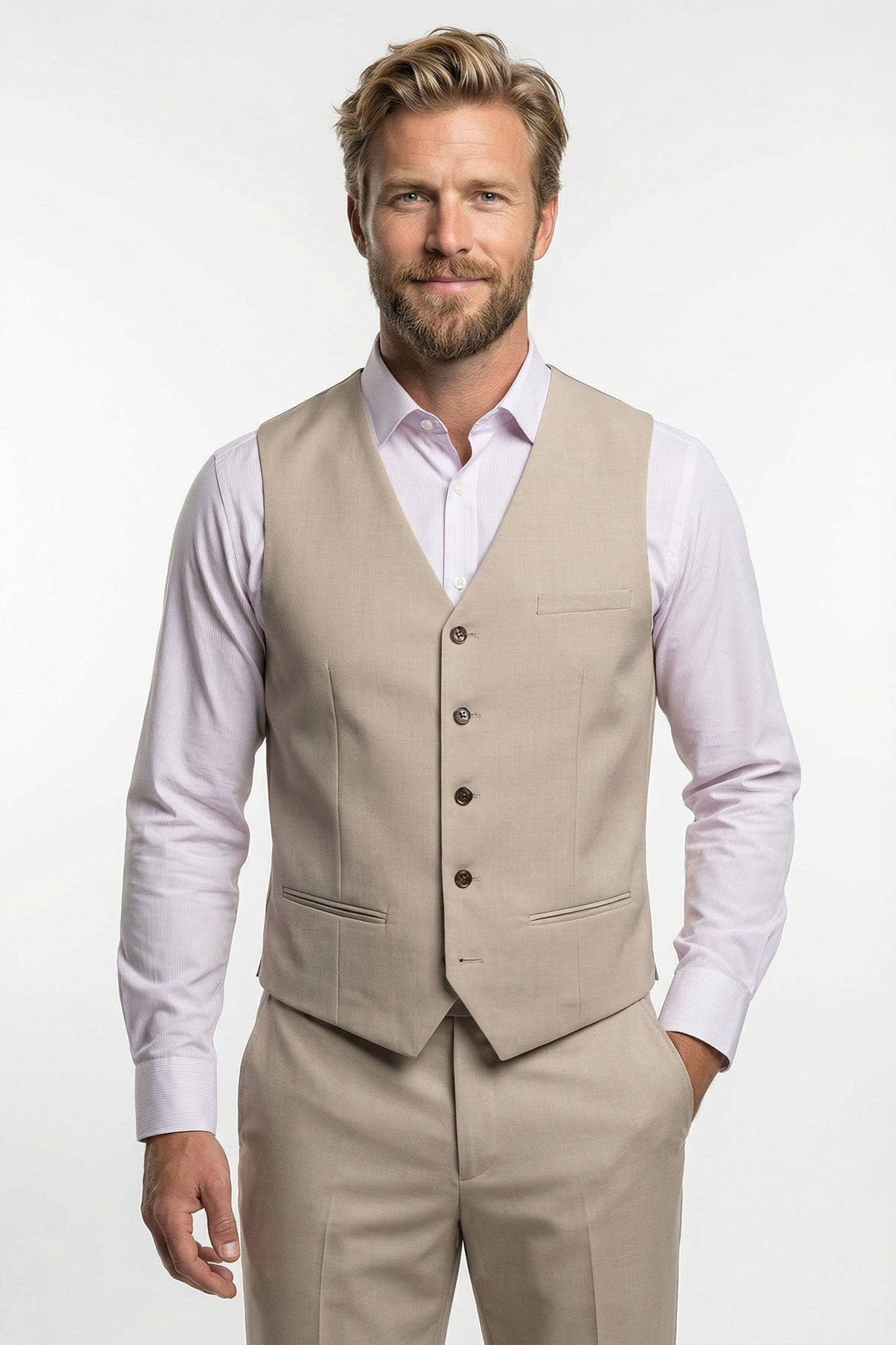 Beige tidløs vest med paspolerede lommer og knapper foran, båret over lyserød skjorte.