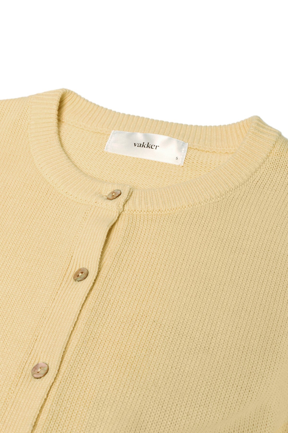 Lys gul cardigan i finstrik med rund hals og knapper foran.