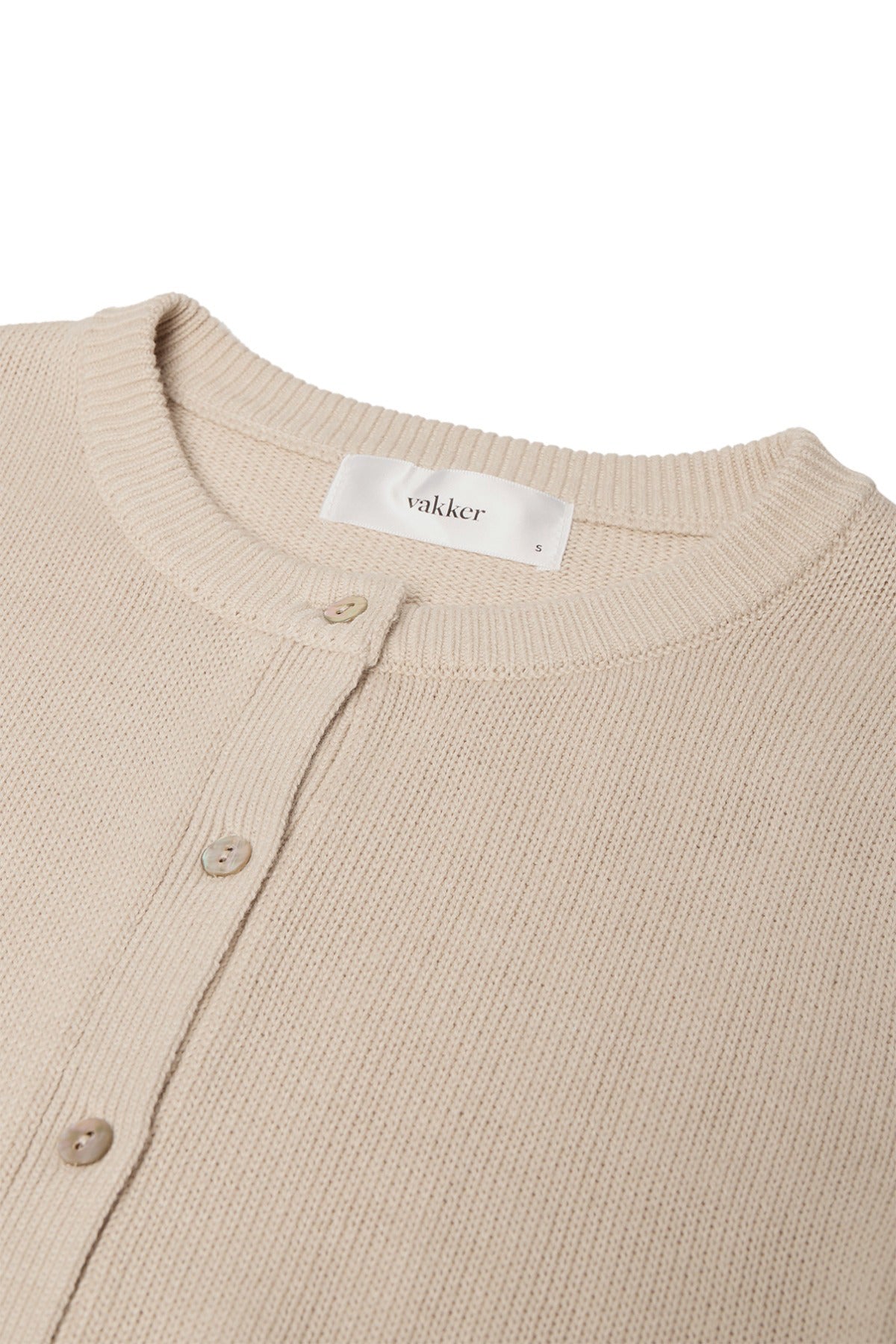 Beige strikket cardigan med rund hals og knapper foran i blød tekstur.