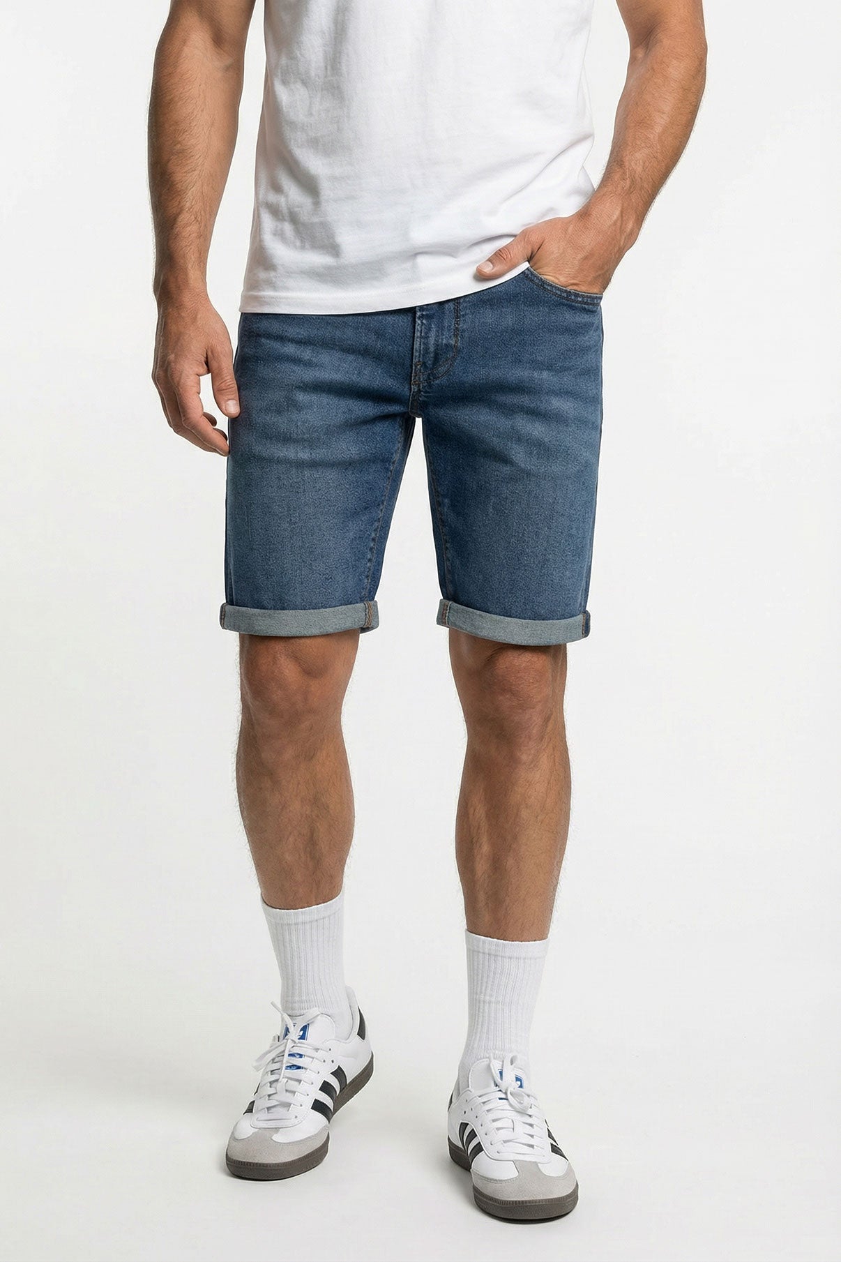 Herre denimshorts i medium indigo med opkrogede ben og skjult lynlås, kombineret med hvid t-shirt og sneakers.
