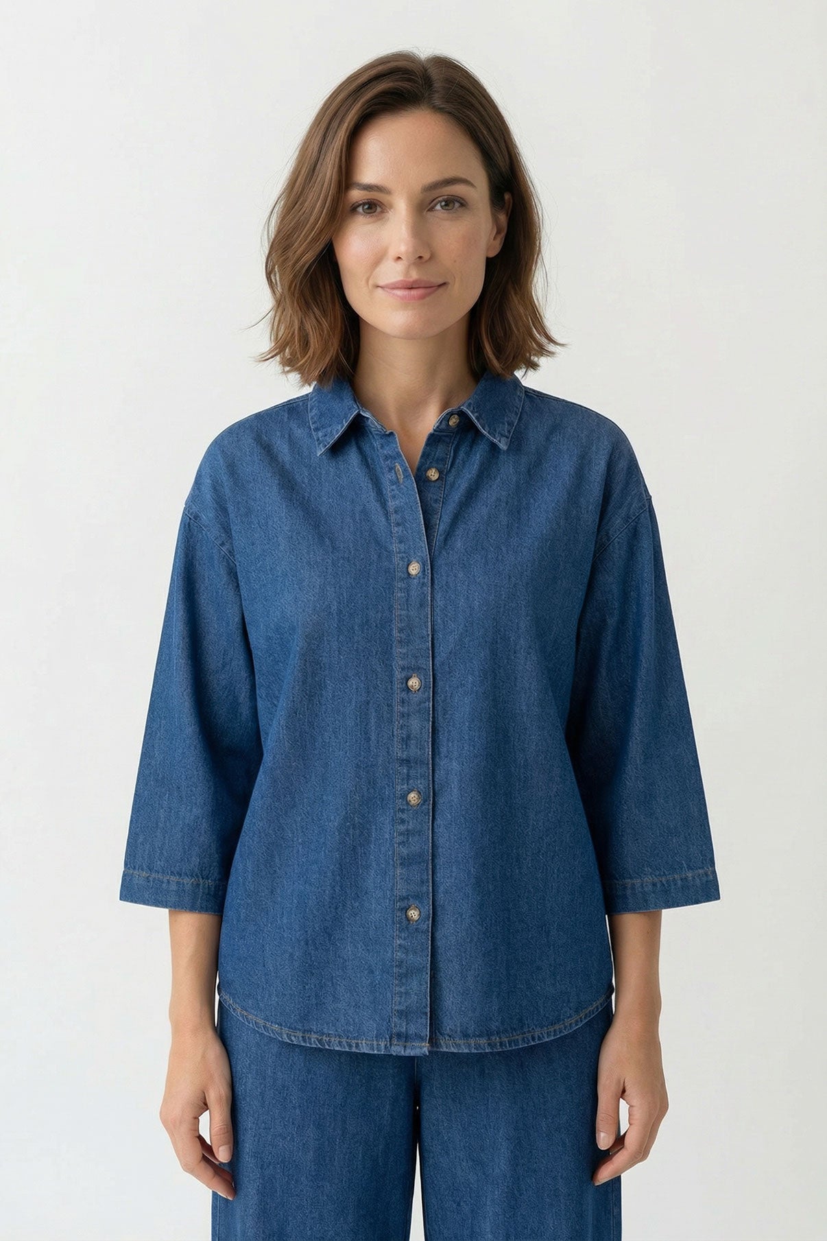 Mørk denimskjorte med trekvartærmer og knapper, klassisk krave og afslappet pasform.