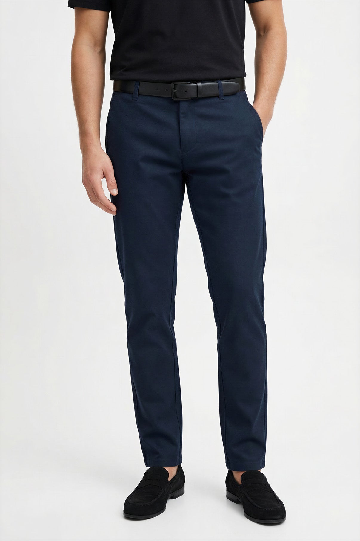 Mørkeblå tapered bukser i strækbart materiale med bælte og sort t-shirt.
