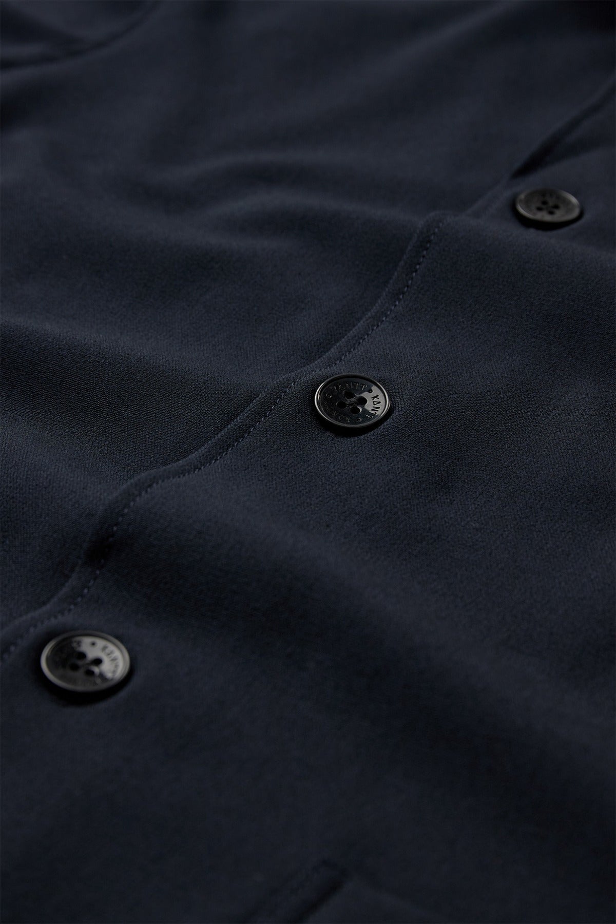 Mørkeblå stretchbar overshirt med sorte knapper og synlige sømme.