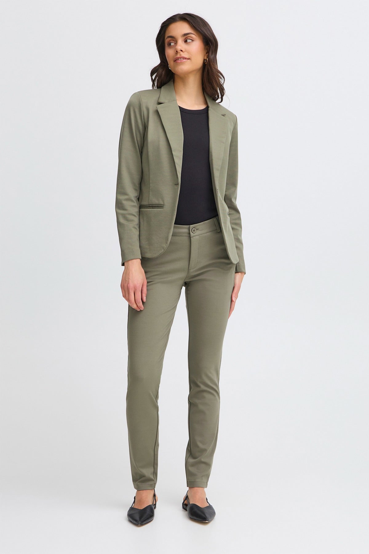 Klassisk Dusty Olive blazer i regular fit med knapper og lommer, stylet med sorte bukser og flade sko.