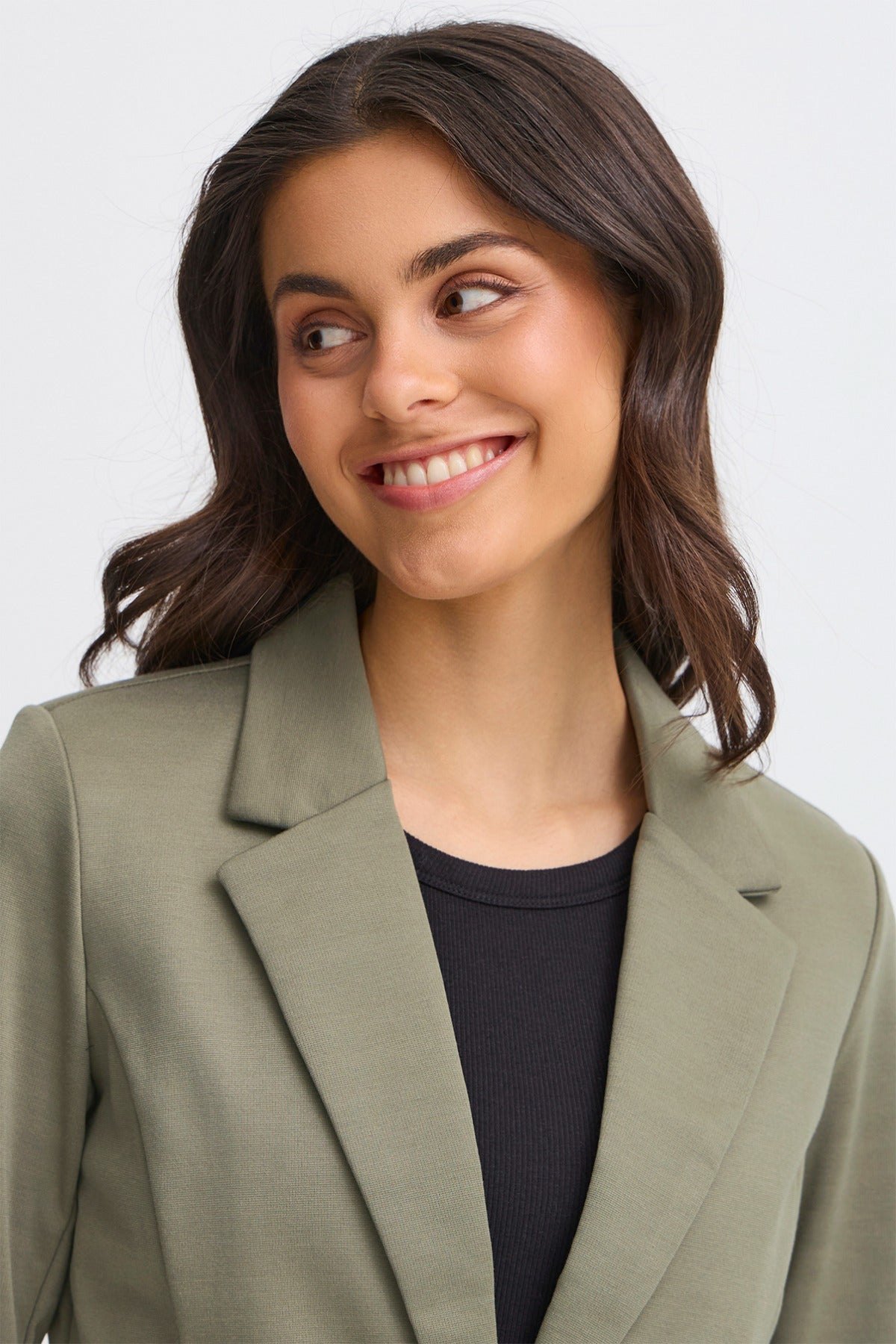 Klassisk dusty olive blazer med reverskrave og regular fit, båret over sort top.