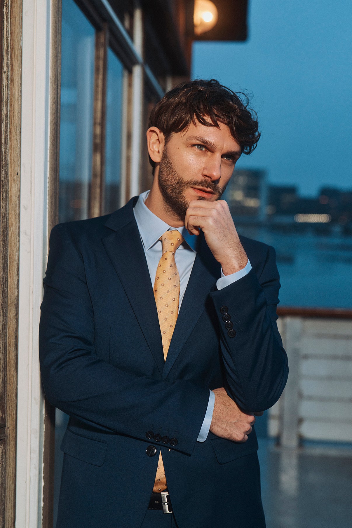 Mørkeblå klassisk blazer med smal pasform, blå skjorte og gul mønstret slips, herrestil.