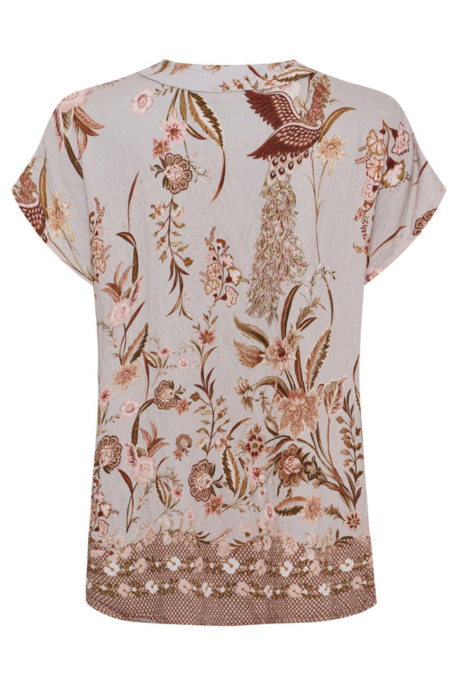 Kortærmet skjortebluse i lys grå med brune og rosa blomster- og fuglemønstre, rund hals og opkrogede ærmekanter.