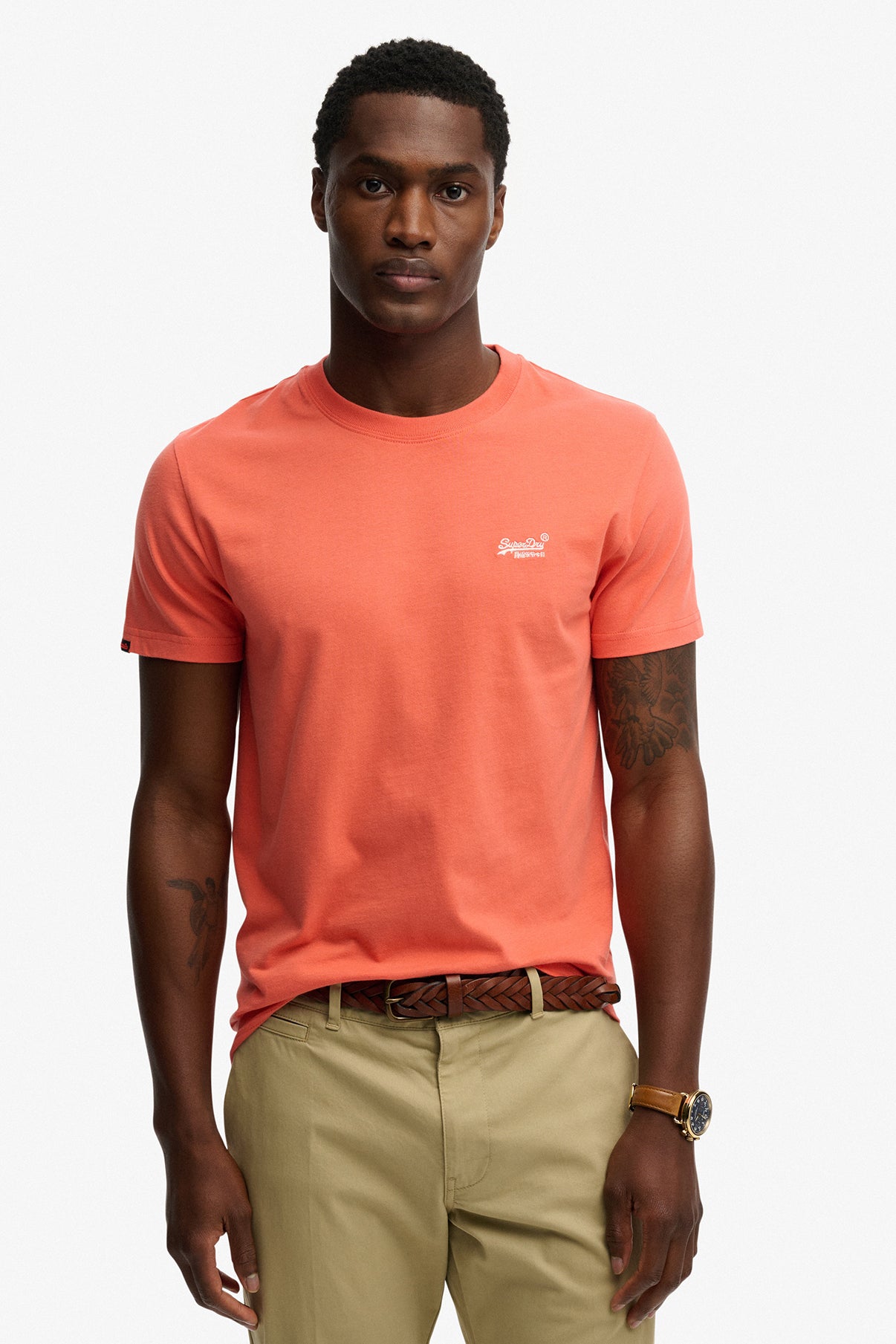 Koralrød t-shirt med rund hals og kontrasthvid broderet logo på brystet, kortærmet.