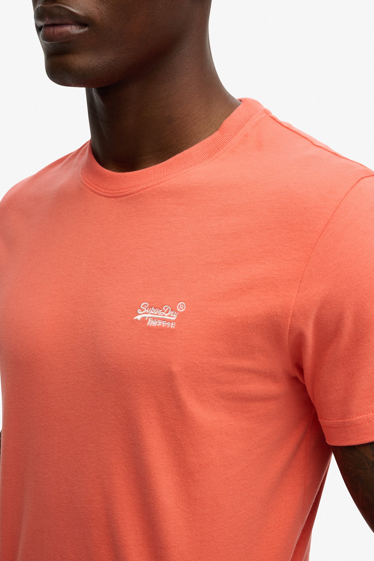 Koralfarvet t-shirt med rund hals og lille hvid logo broderet på venstre bryst.