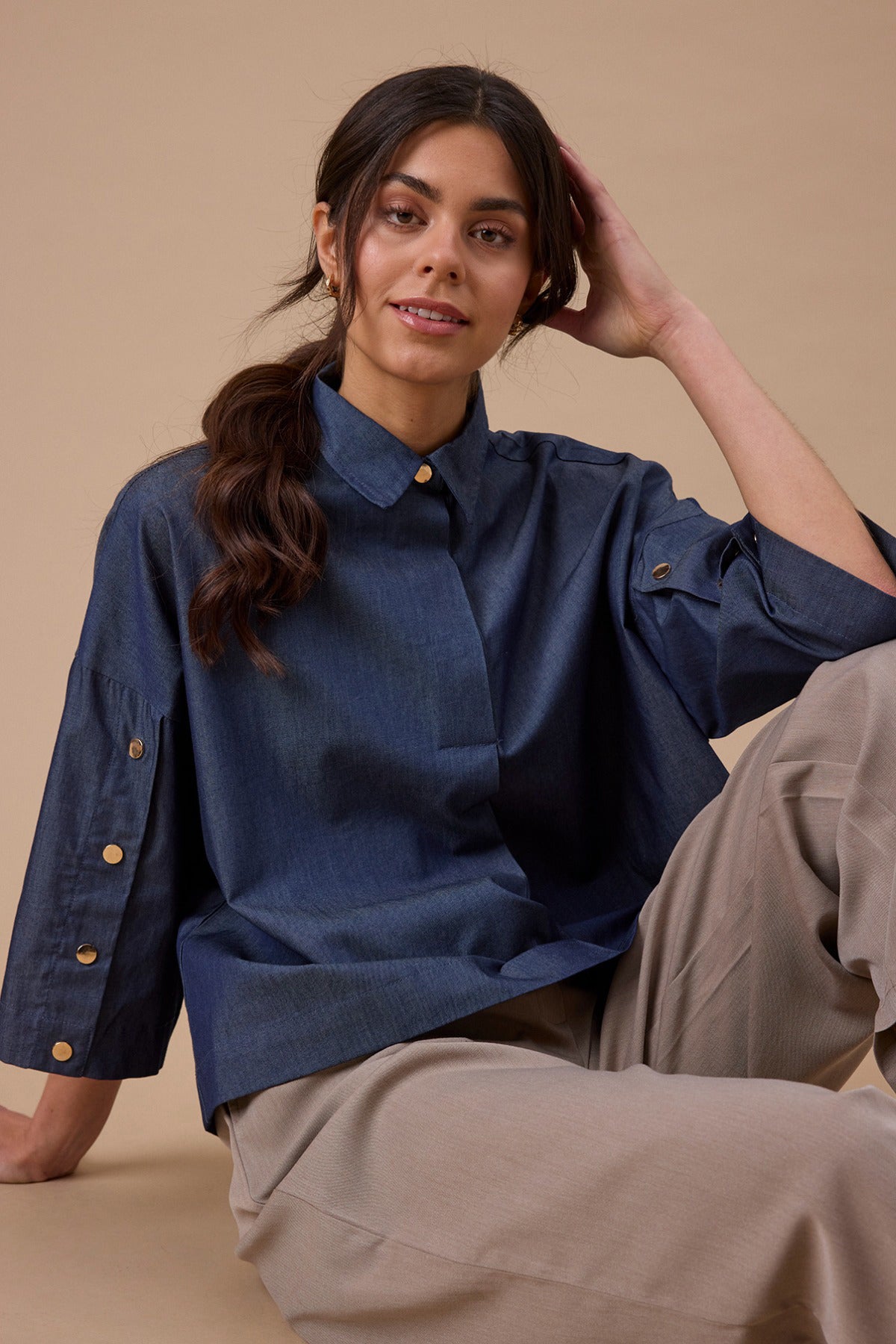 Mid blue denim skjortebluse med trekvartærmer og knapper på ærmer og krave.