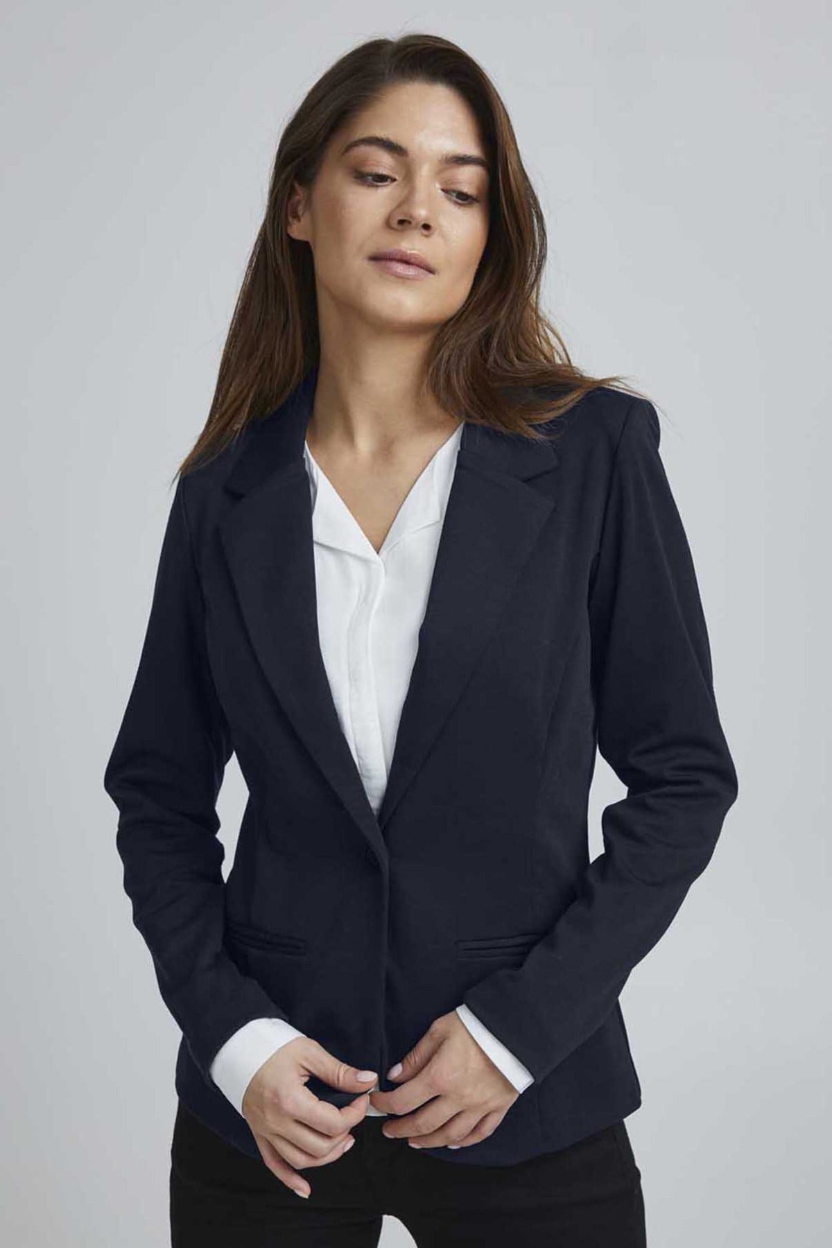 Sort klassisk blazer i regular fit med reverskrave og knaplukning, båret over hvid skjorte.