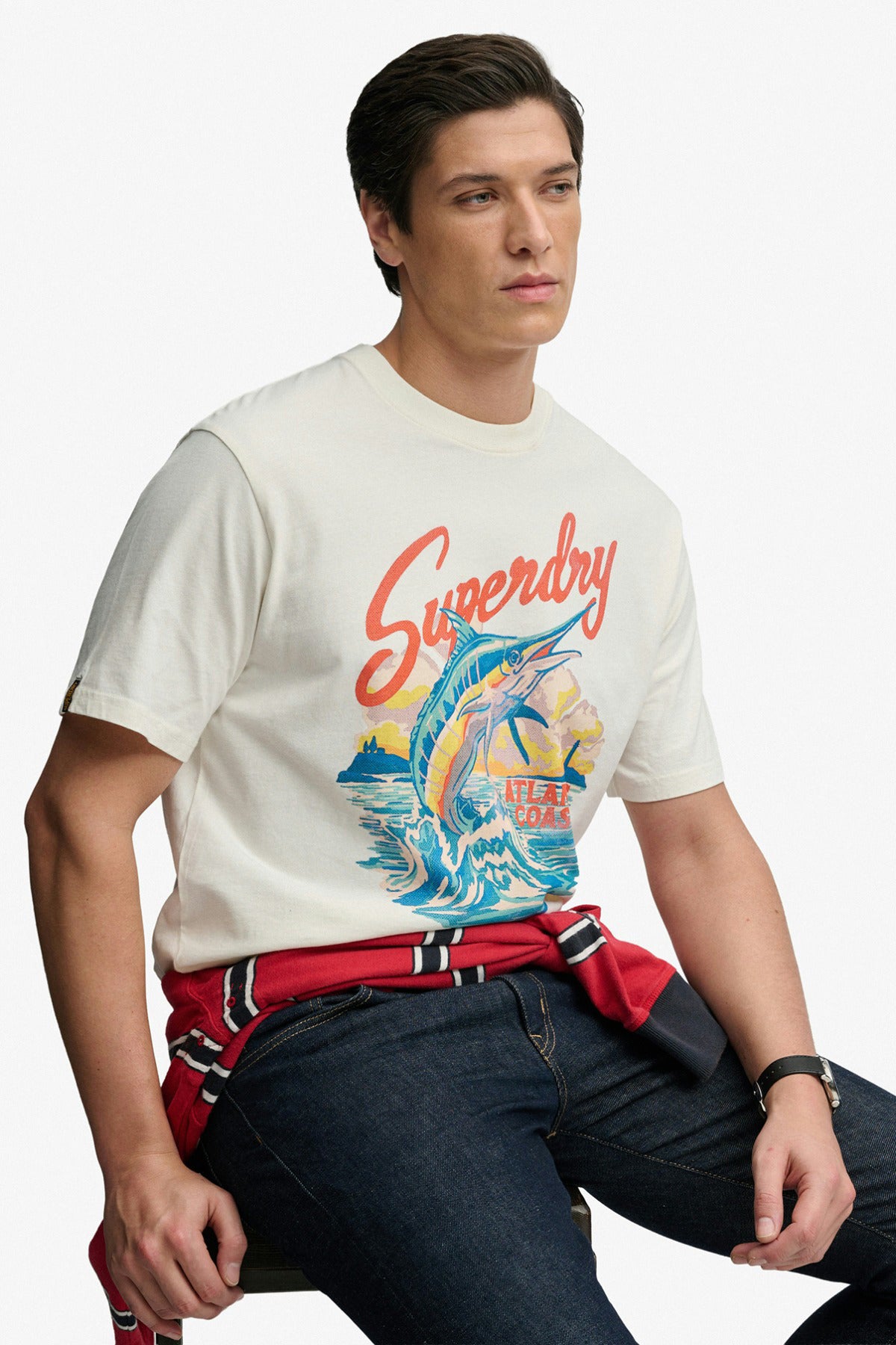 Kortærmet hvid loose fit t-shirt med farverigt tryk og rund hals, styling med bælte og mørke jeans.