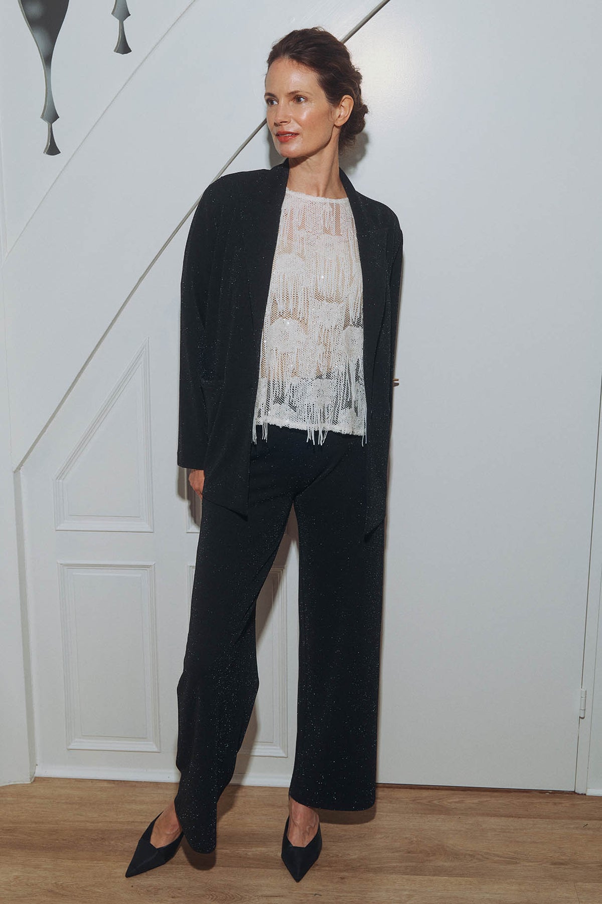 Sort blazer i glitrende stoff med revers, hvit bluse og matchende bukser.