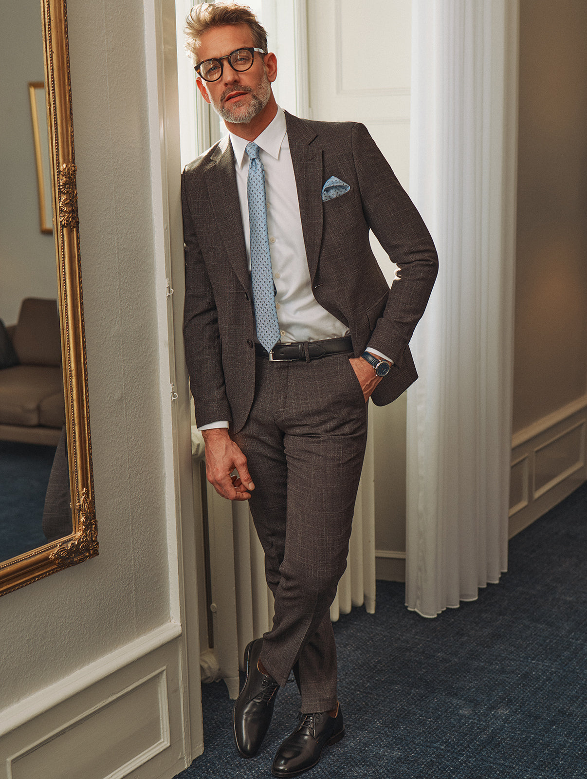 Velklædt mand i brunt jakkesæt med lyseblåt slips og lommeklud..