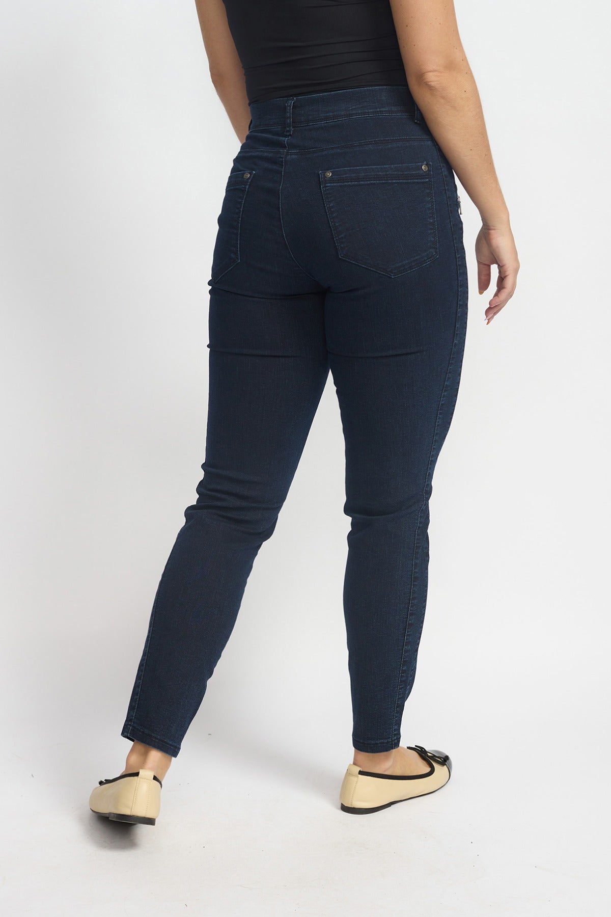 Mørk denimstrækbukser med høj talje og smal 7/8 benlængde set bagfra.