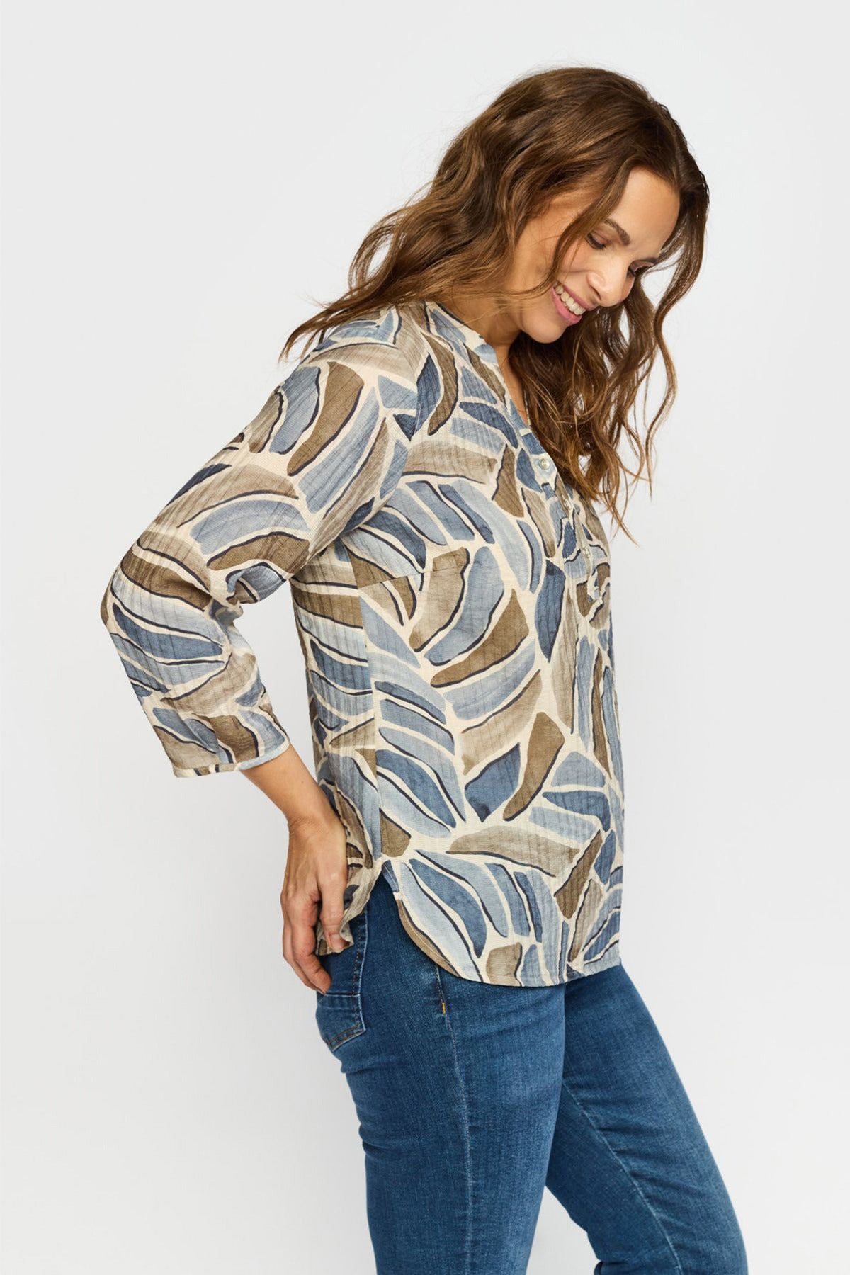 Bluse med abstrakt mønster i beige og blå nuancer, trekvart ærmer, rund hals med knapper foran.