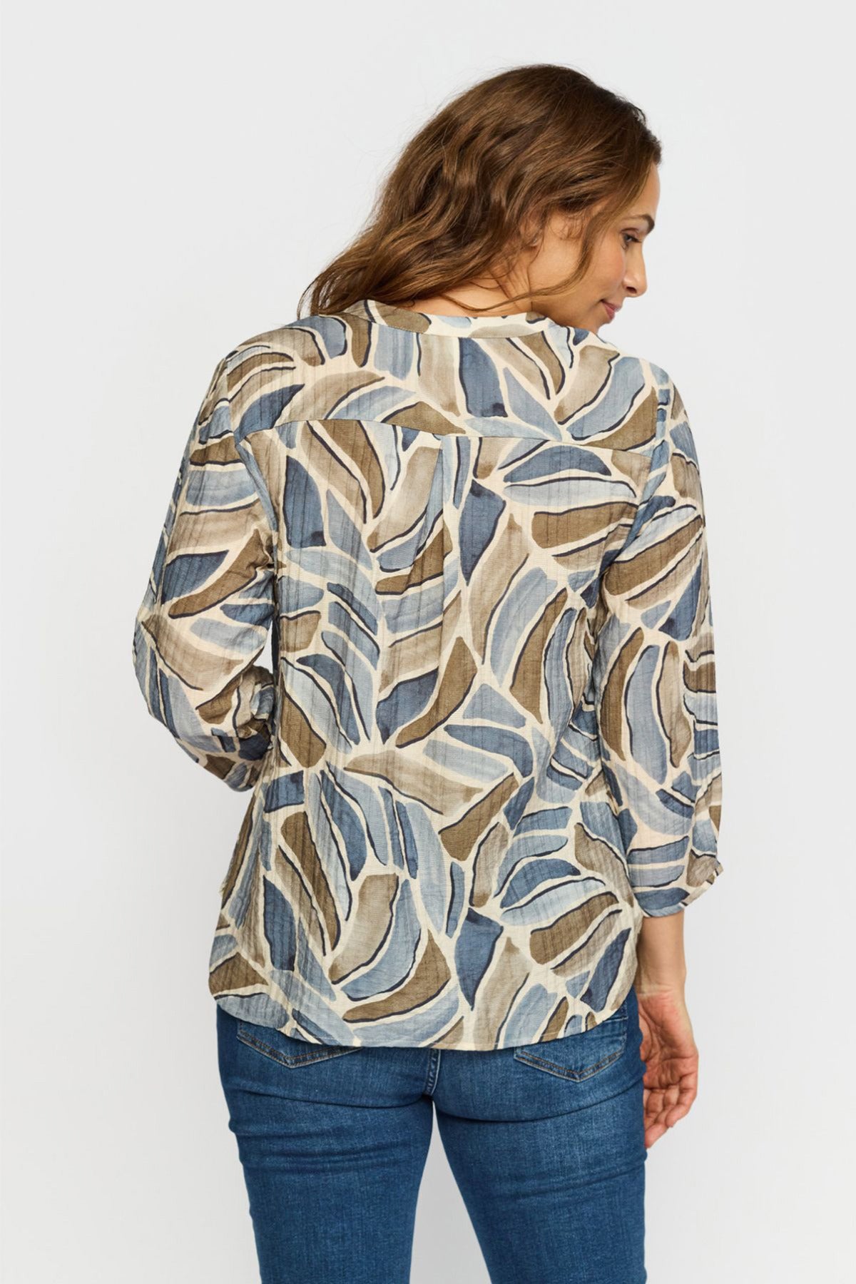 Bluse med mønster i blå og beige nuancer, trekvartærmer og løs pasform set bagfra.
