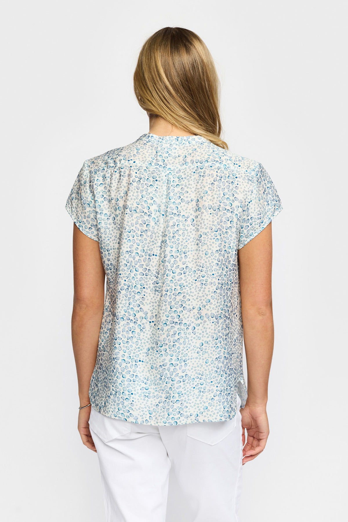 Kortærmet bluse med let blå prikprint og rundet sømdetalje bagpå.