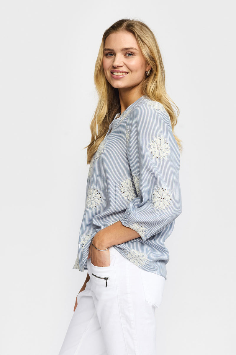 Lyseblå skjortebluse med hvide blomsterprint og trekvartærmer, afslappet pasform.