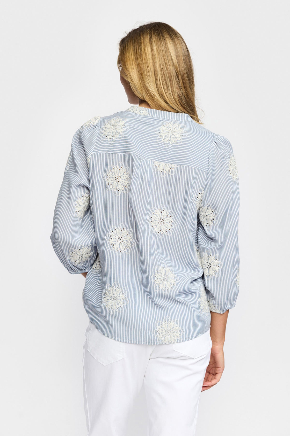 Lyseblå skjortebluse med hvide blomsterprint og trekvartærmer set bagfra.