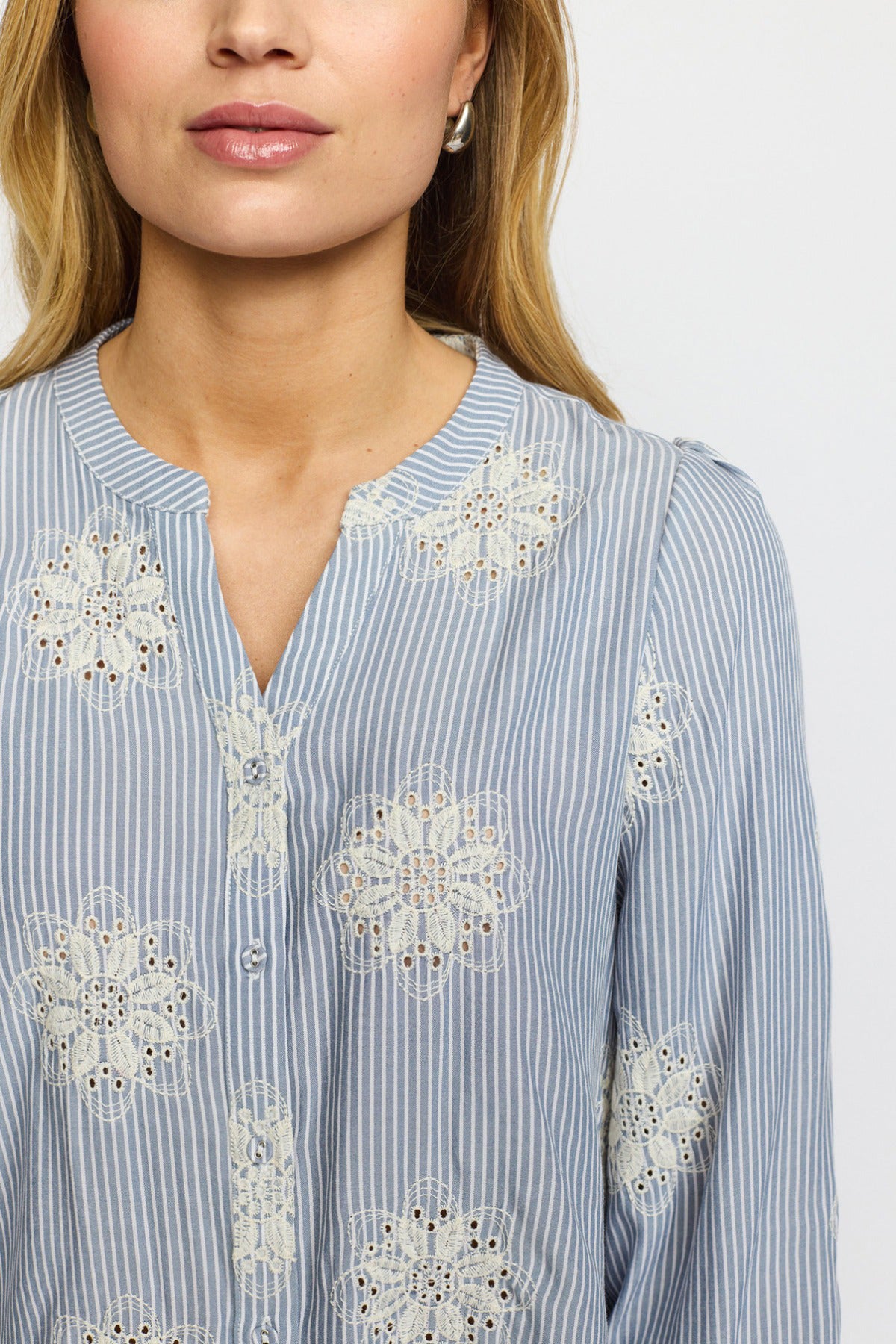 Blå- og hvidstribet skjortebluse med trekvartærmer og broderede blomsterdetaljer.