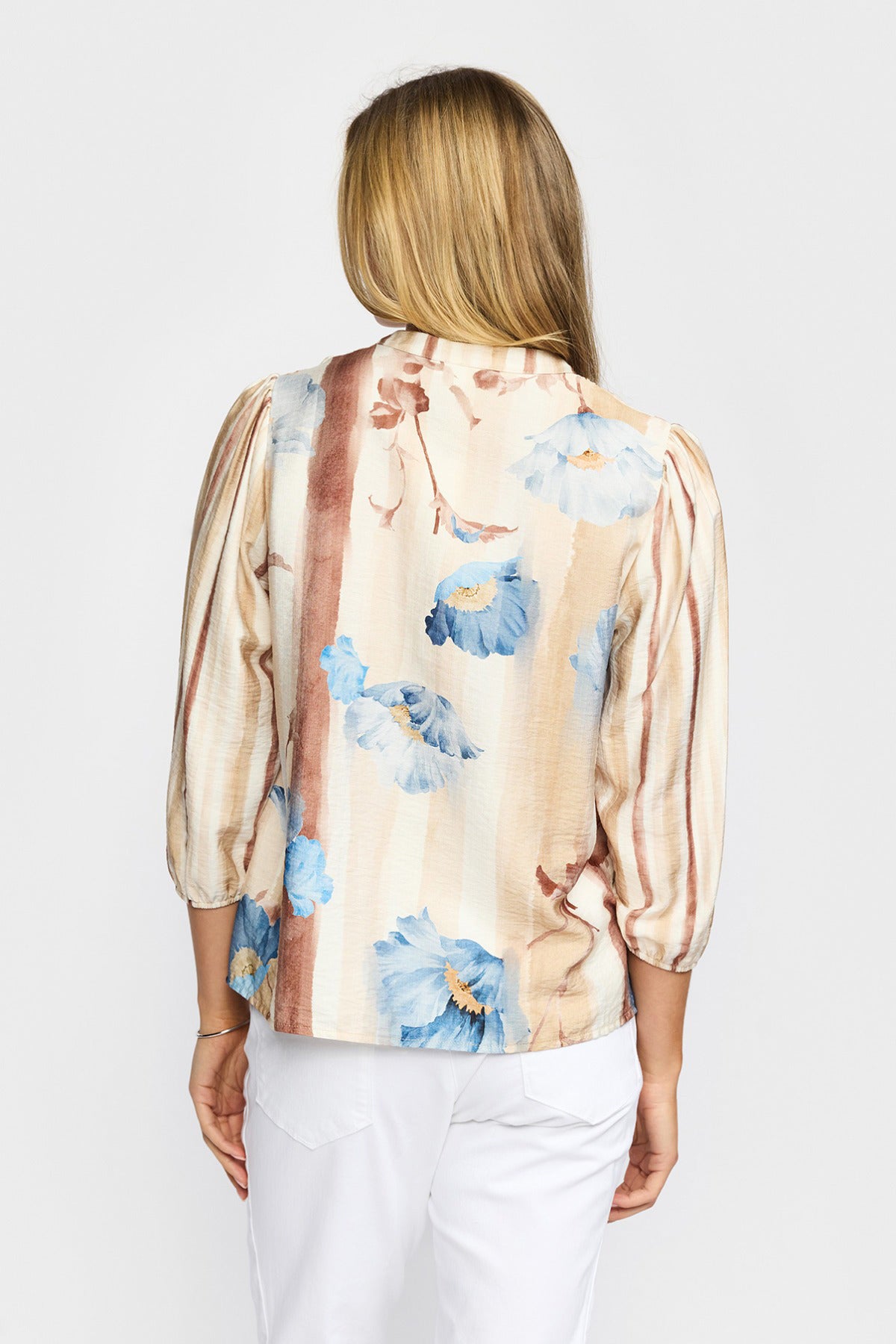 Cremefarvet bluse med trekvartærmer, blå blomsterprint og beige striber bagfra.