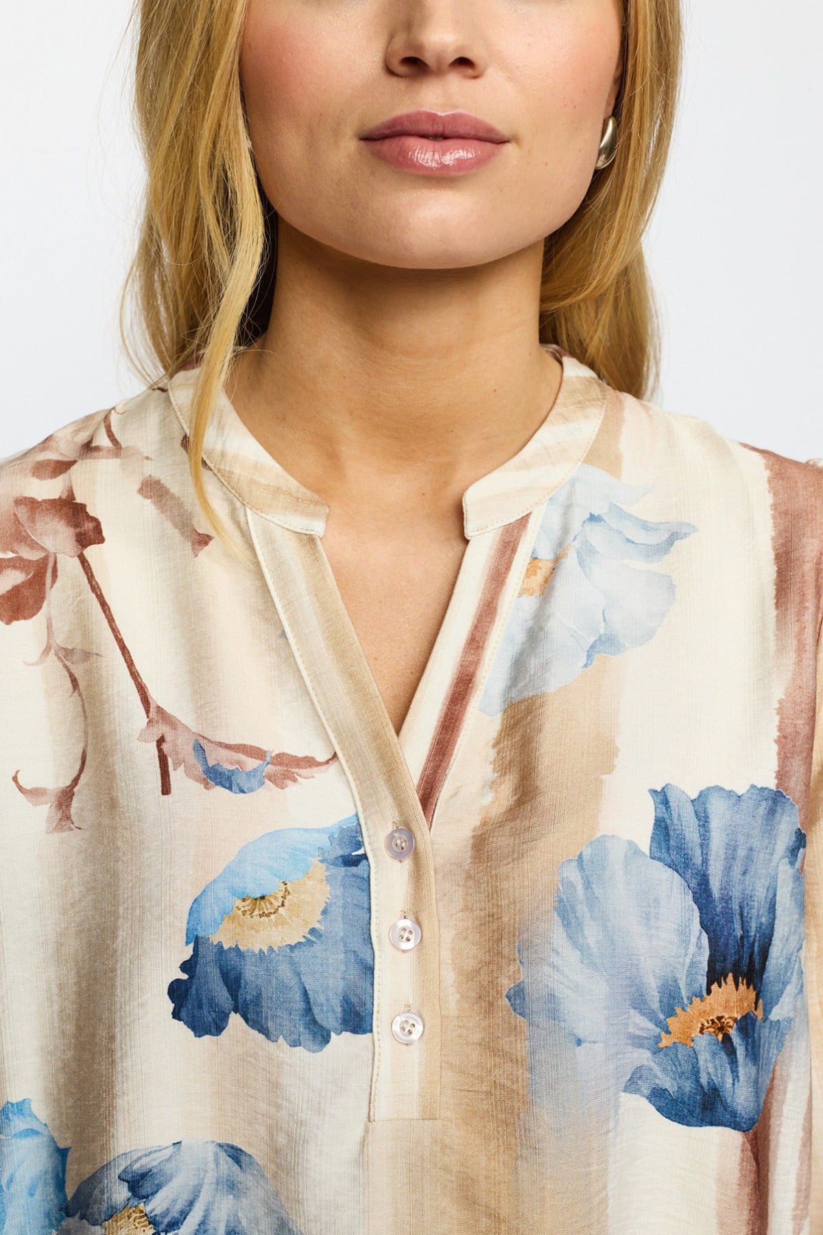 Beige bluse med sandfarvet blomsterprint og trekvartærmer, let krave med knapper.