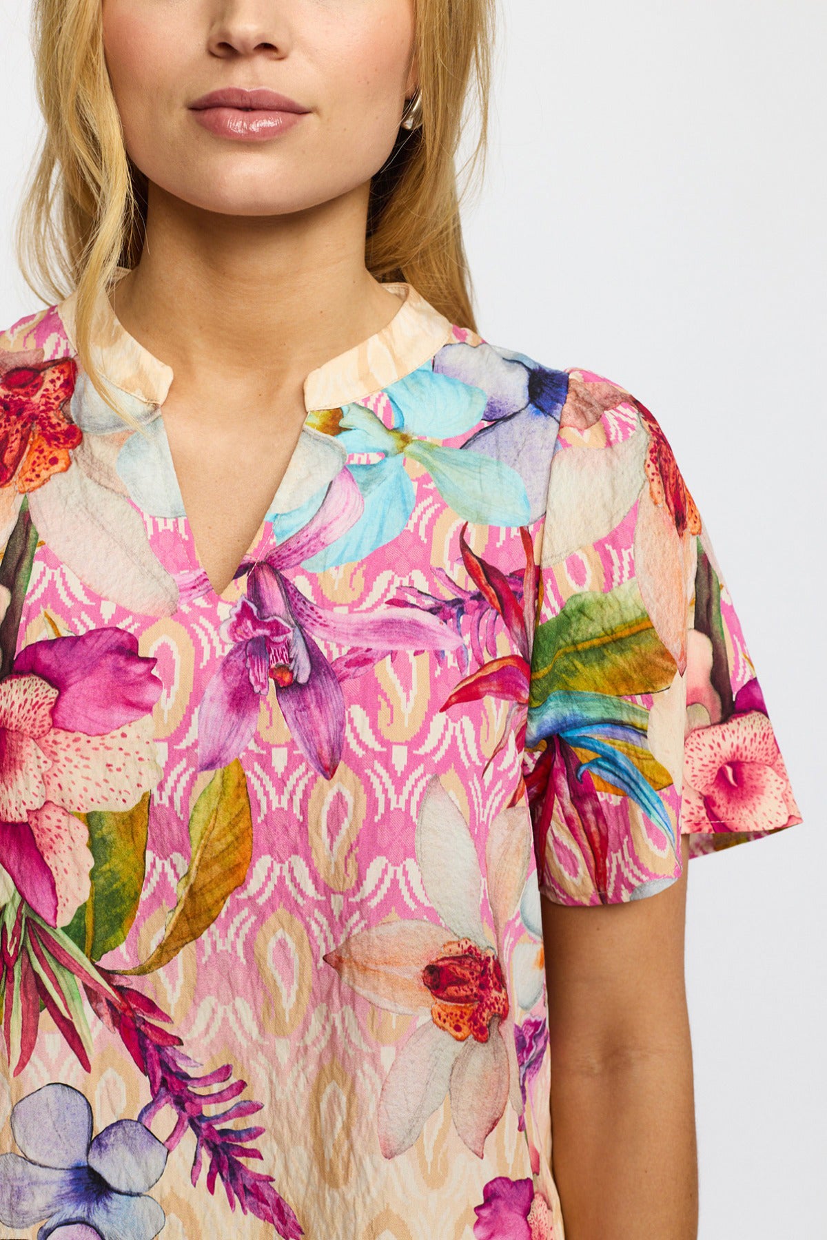 Kortærmet bluse med farverigt blomsterprint og rundet hals med slids i pastelnuancer.