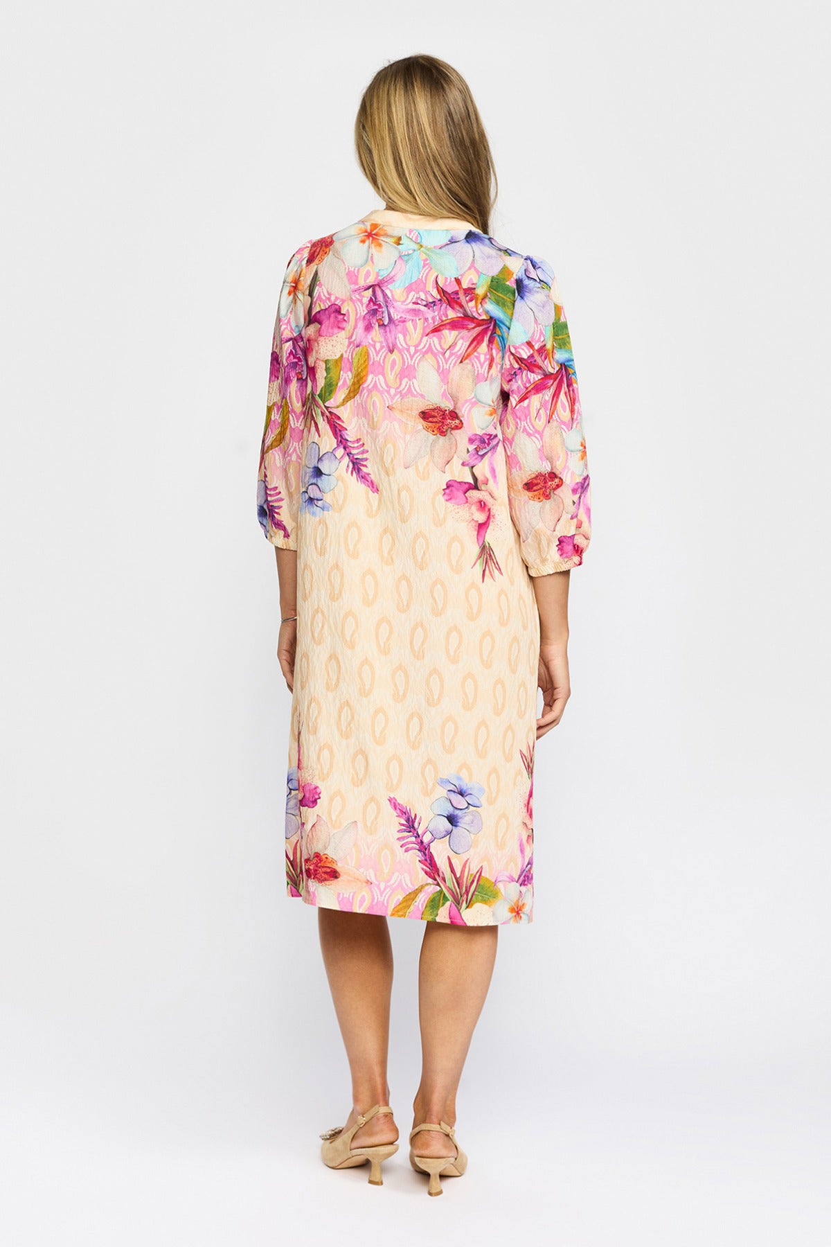 Beige midikjole med farvestrålende blomsterprint og trekvartærmer, set bagfra.
