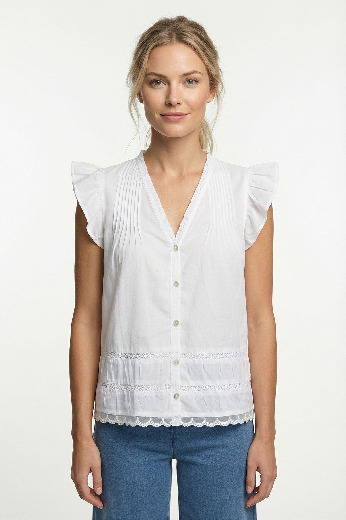 Hvid skjortebluse med flæser på ærmer og broderi langs front og bund.