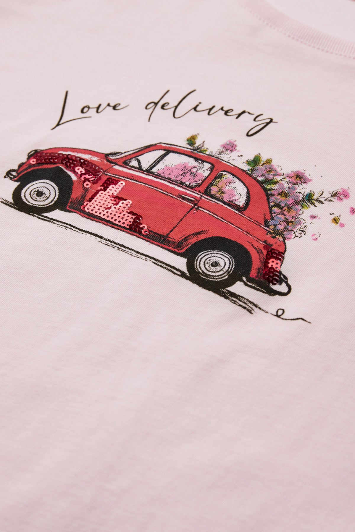 Lys rosa bomulds t-shirt med rød vintage bil og blomstermotiv, tekst "Love delivery".