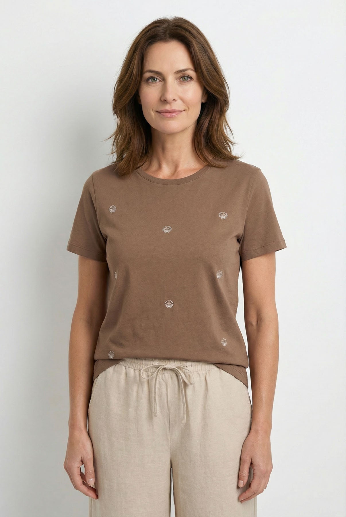 Brun bomulds t-shirt med korte ærmer og små dekorative blomsterdetaljer foran.
