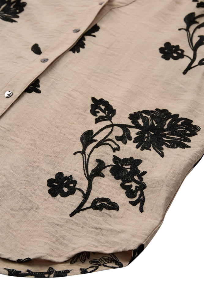 Beige skjortebluse med sort blomsterprint og trekvartærmer i let krøllet stof.