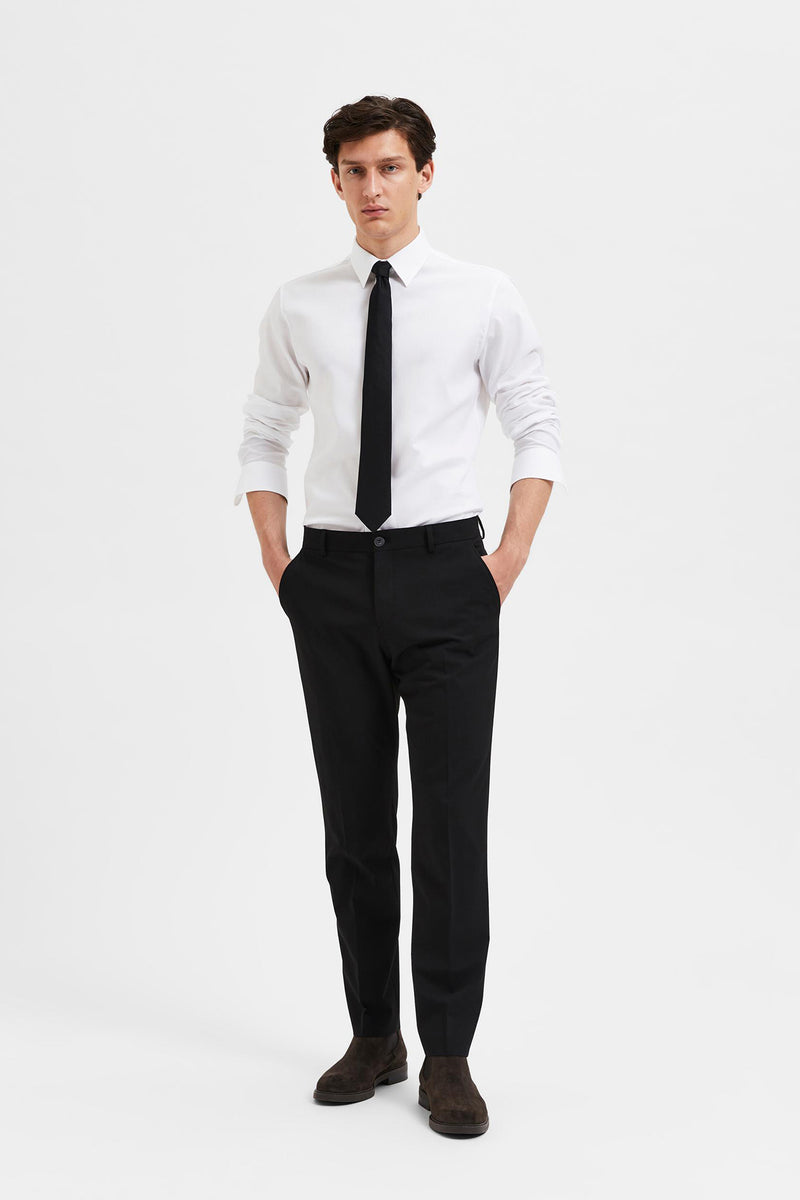 Sort slim fit bukser med lige ben, brugt med hvid skjorte og sort slips.