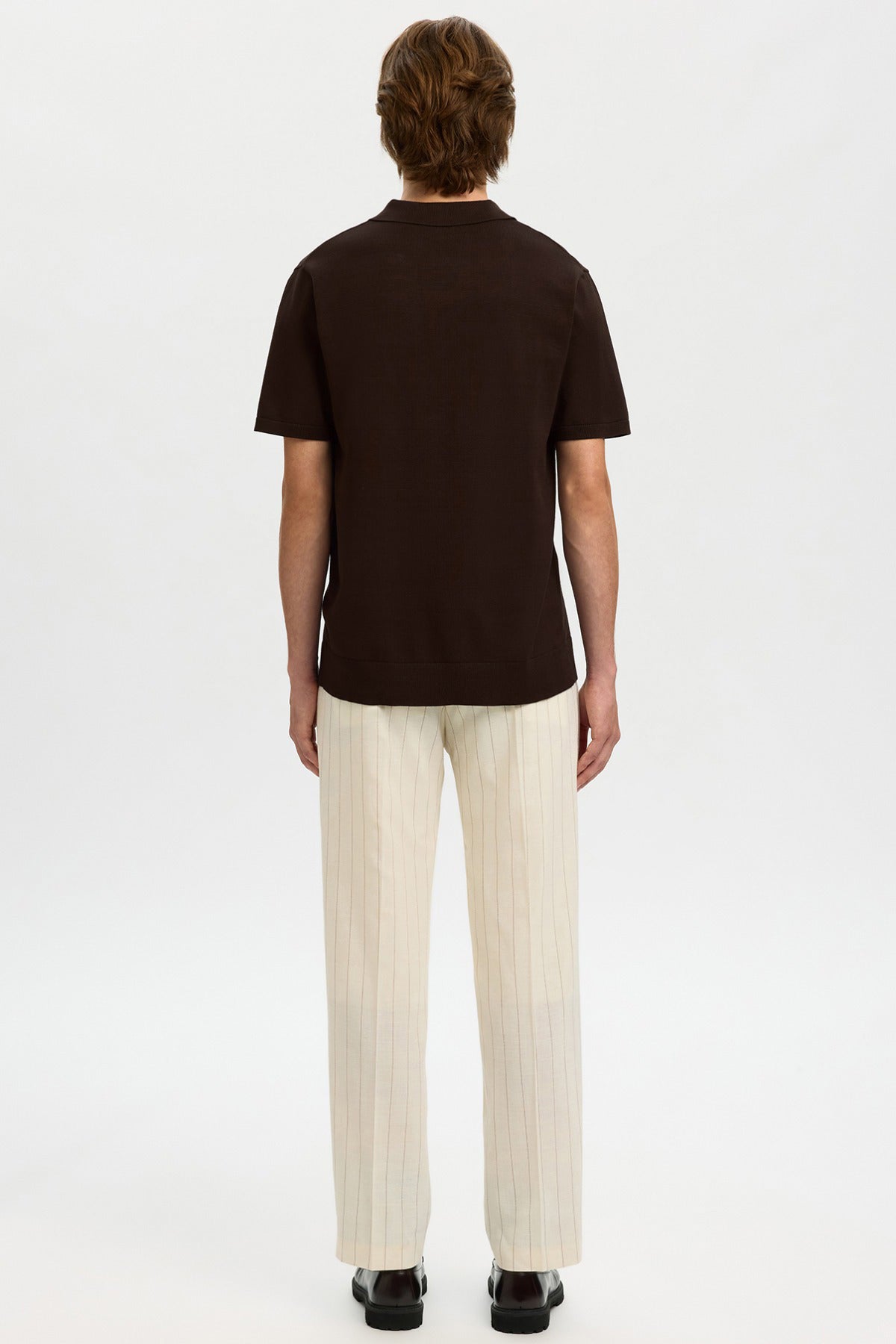 Brun kortærmet strikket polo med krave og beige løse bukser set bagfra.