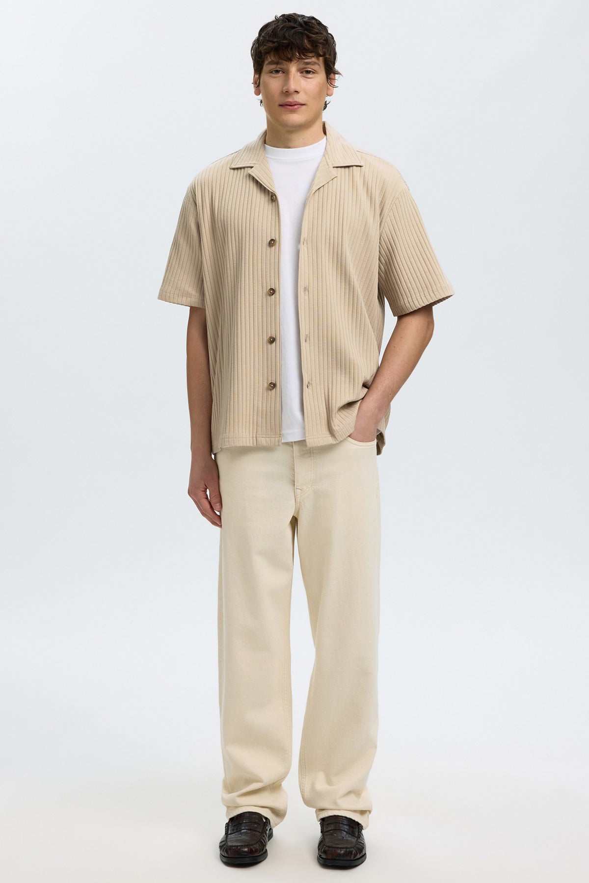 Beige kortærmet ribstrikket overshirt med knapper stylet med beige bukser og hvid t-shirt.