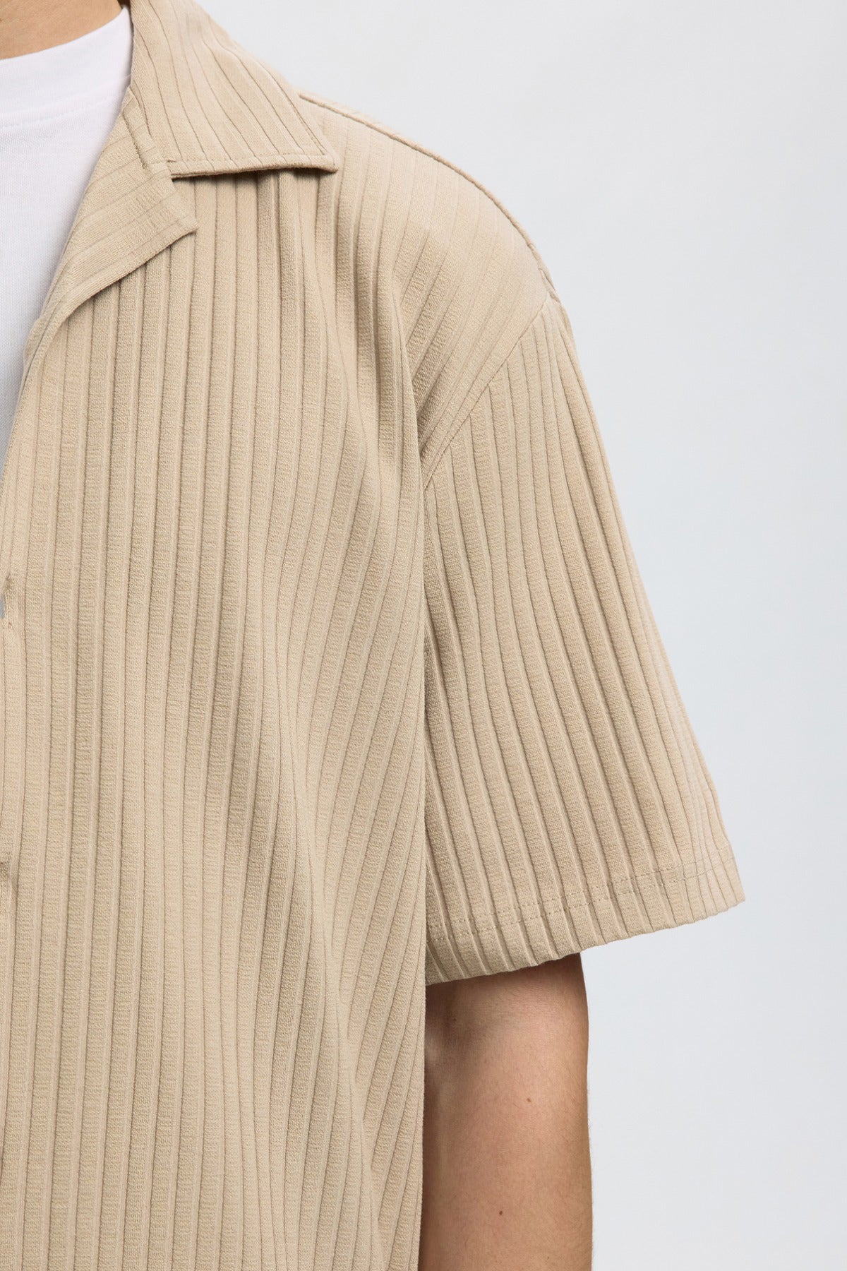 Beige kortærmet overshirt i ribstrikket stof med krave og knaplukning.
