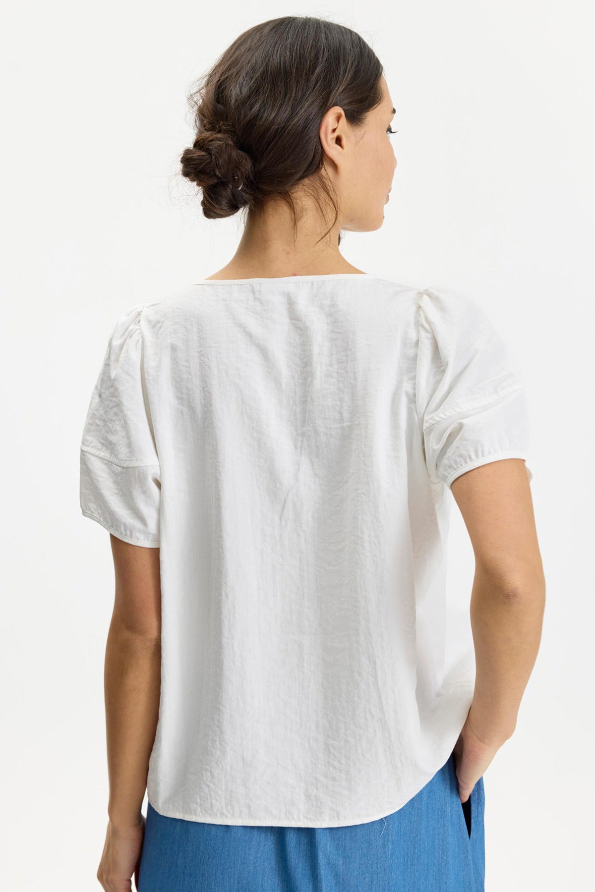 Hvid Filippa bluse med korte pufærmer og tekstureret stof set bagfra.
