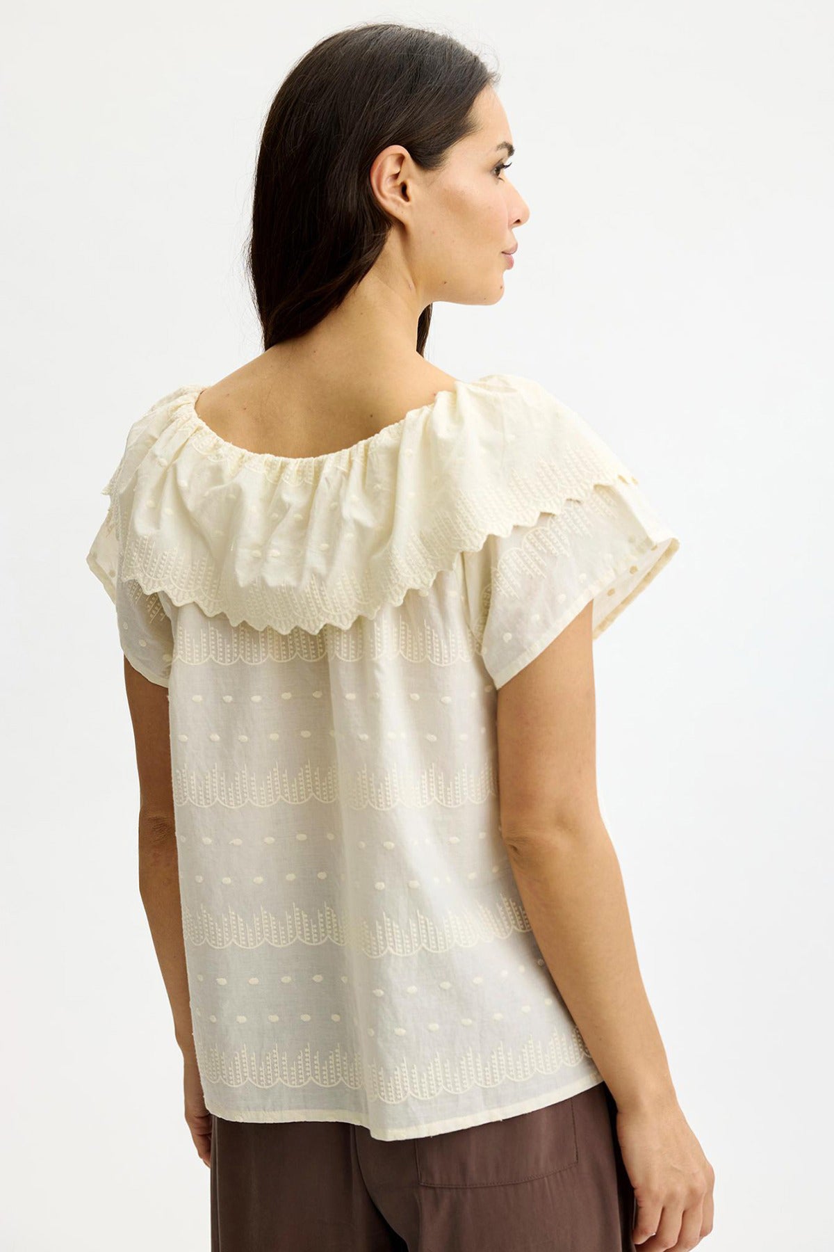 Cremefarvet bluse med flæsekrave og korte ærmer i let, transparent stof.