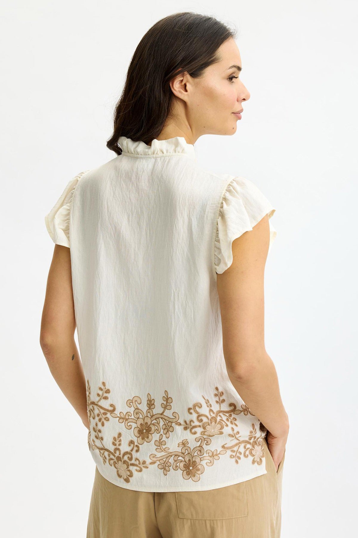 Offwhite top med flæsekrave og ærmer, broderi langs nedre kant bagpå.