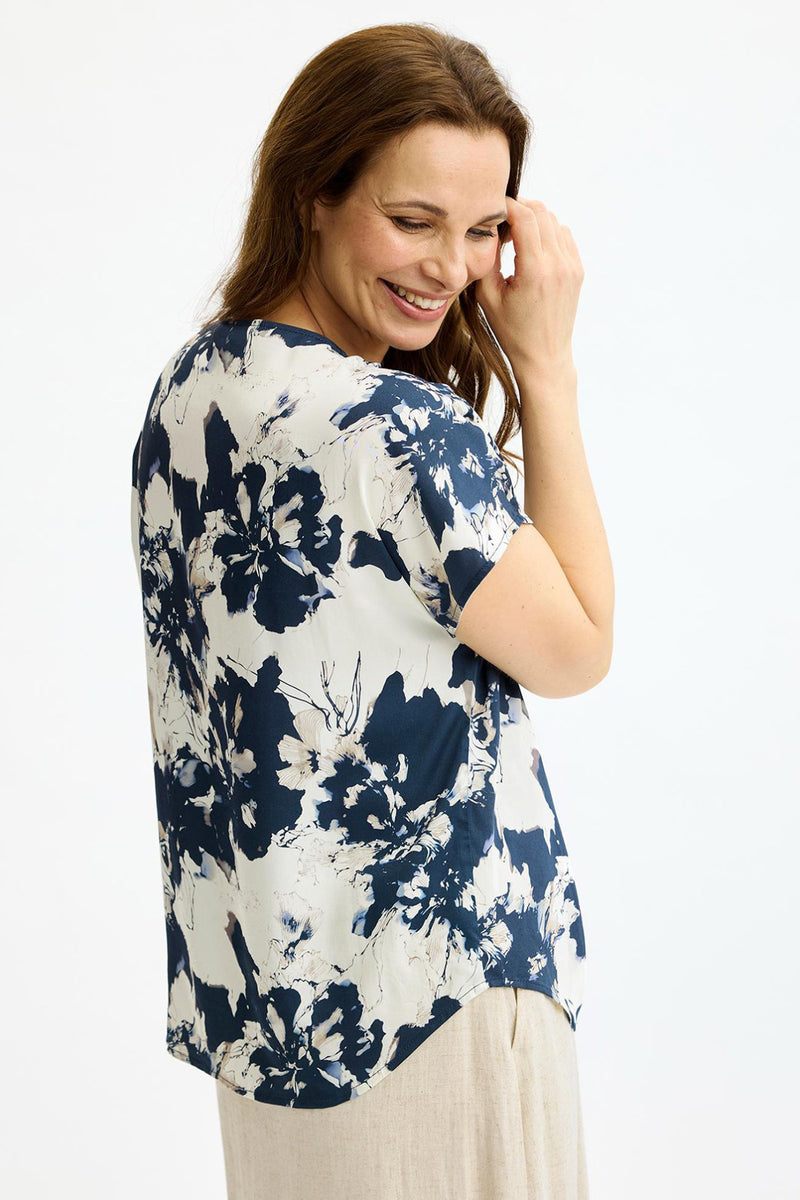 Blå og hvid bluse med store blomsterprint og fine syningsdetaljer på ryggen.
