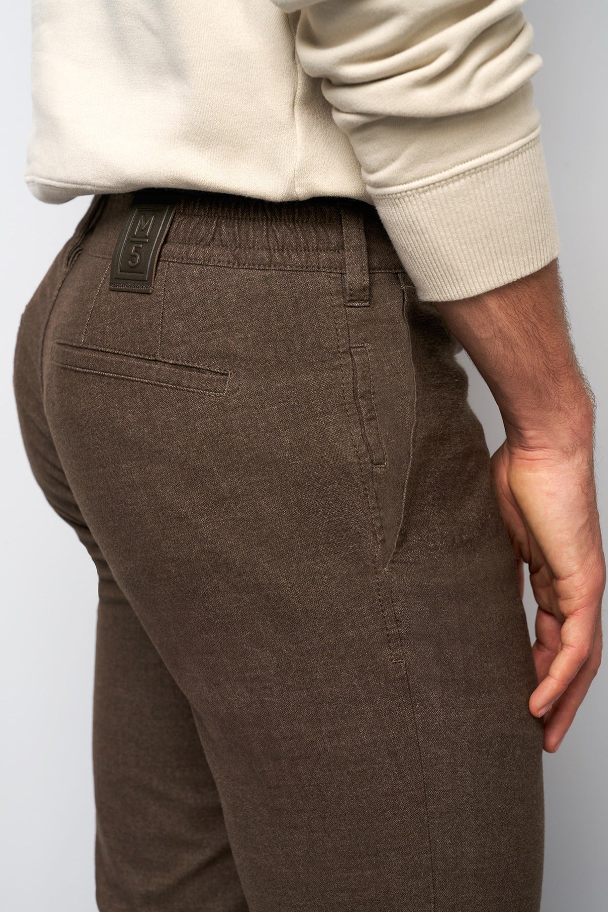 Brune flannel chinos med elastisk pasform og skrå lommer, set fra siden.