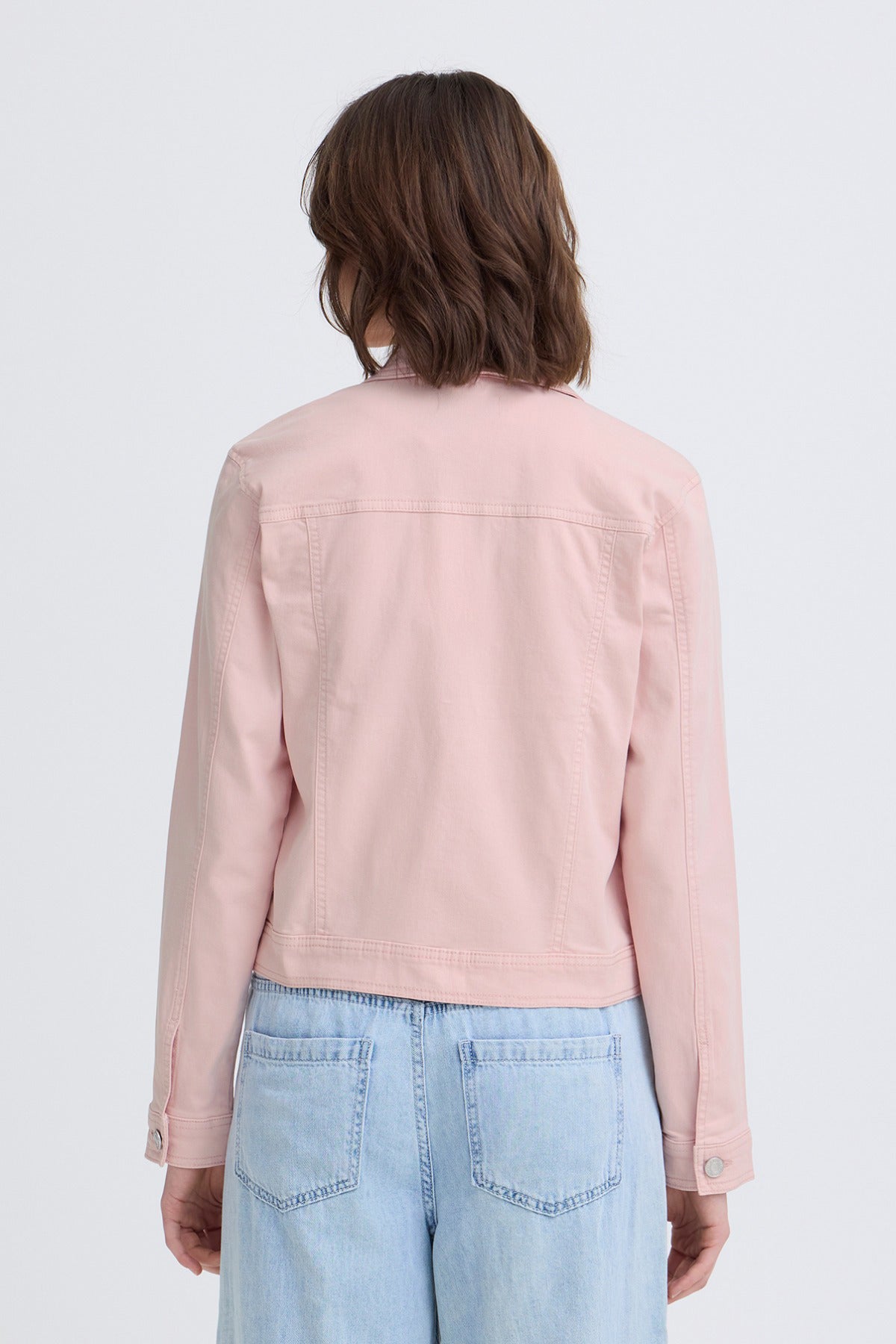Lyserød elastisk denimjakke med lange ærmer og baglommer, set bagfra.