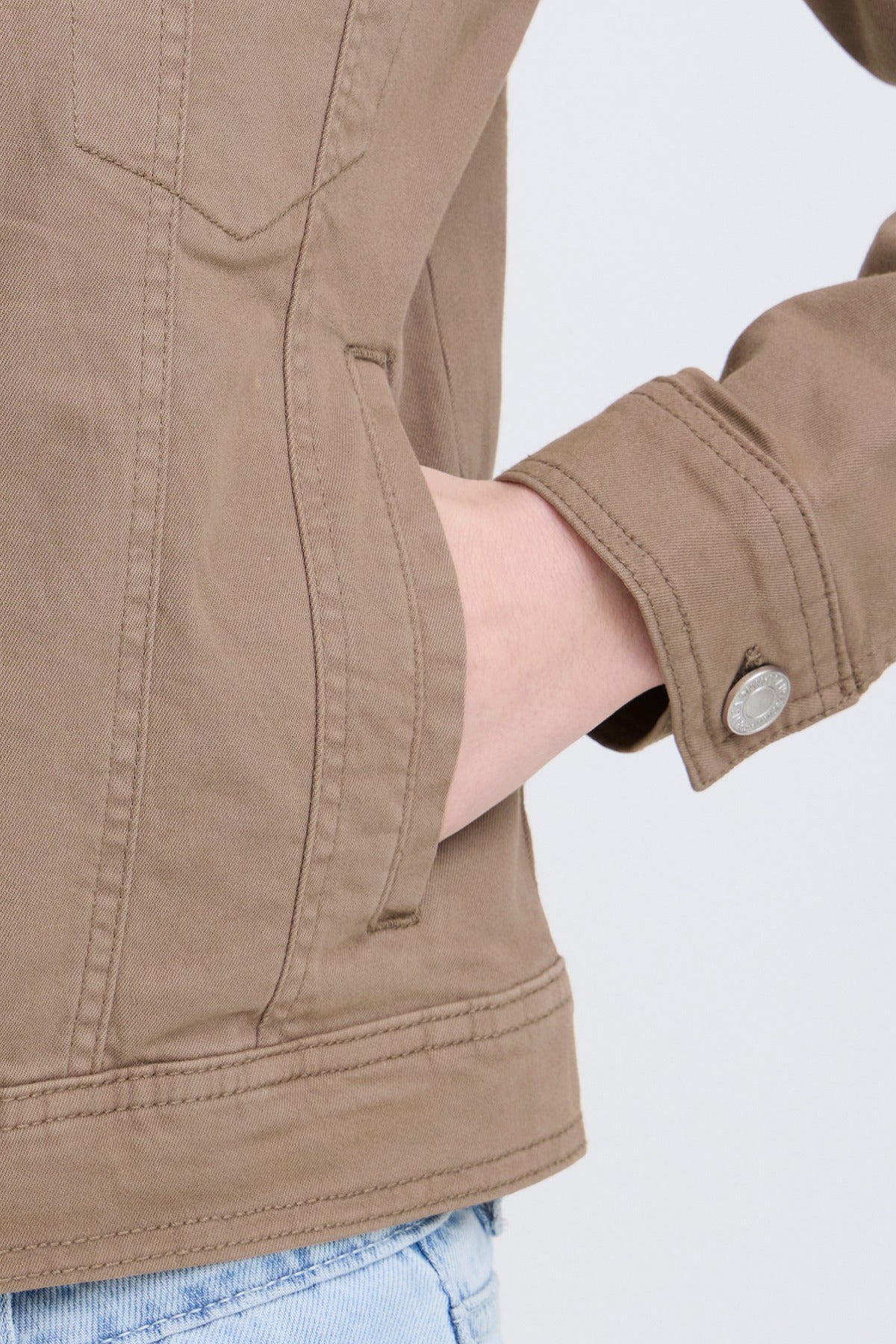 Elastisk denimjakke i beige med sidelomme og metalknap ved manchet.